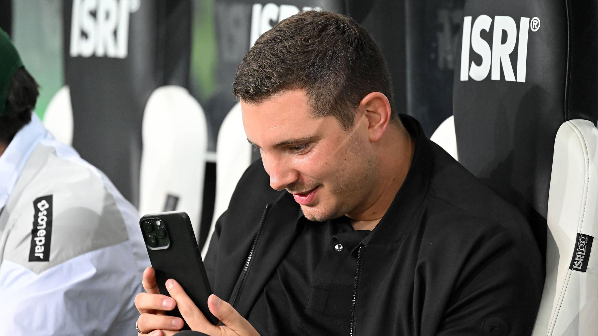 Nils Schmadtke schaut begeistert auf sein Smartphone.