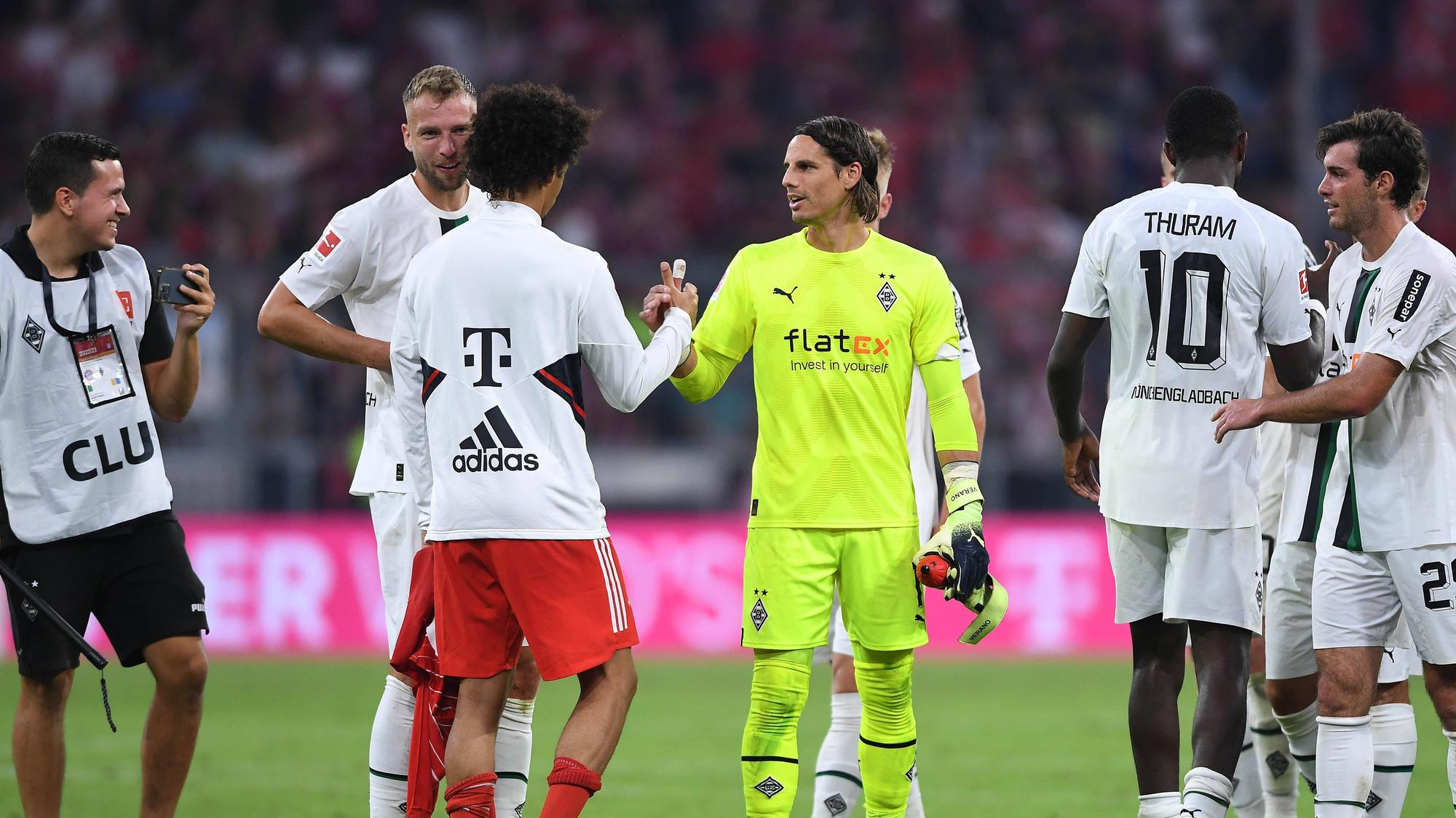 Spieler von Borussia Mönchengladbach klatschen nach Spielende mit einem Profi vom FC Bayern München ab.