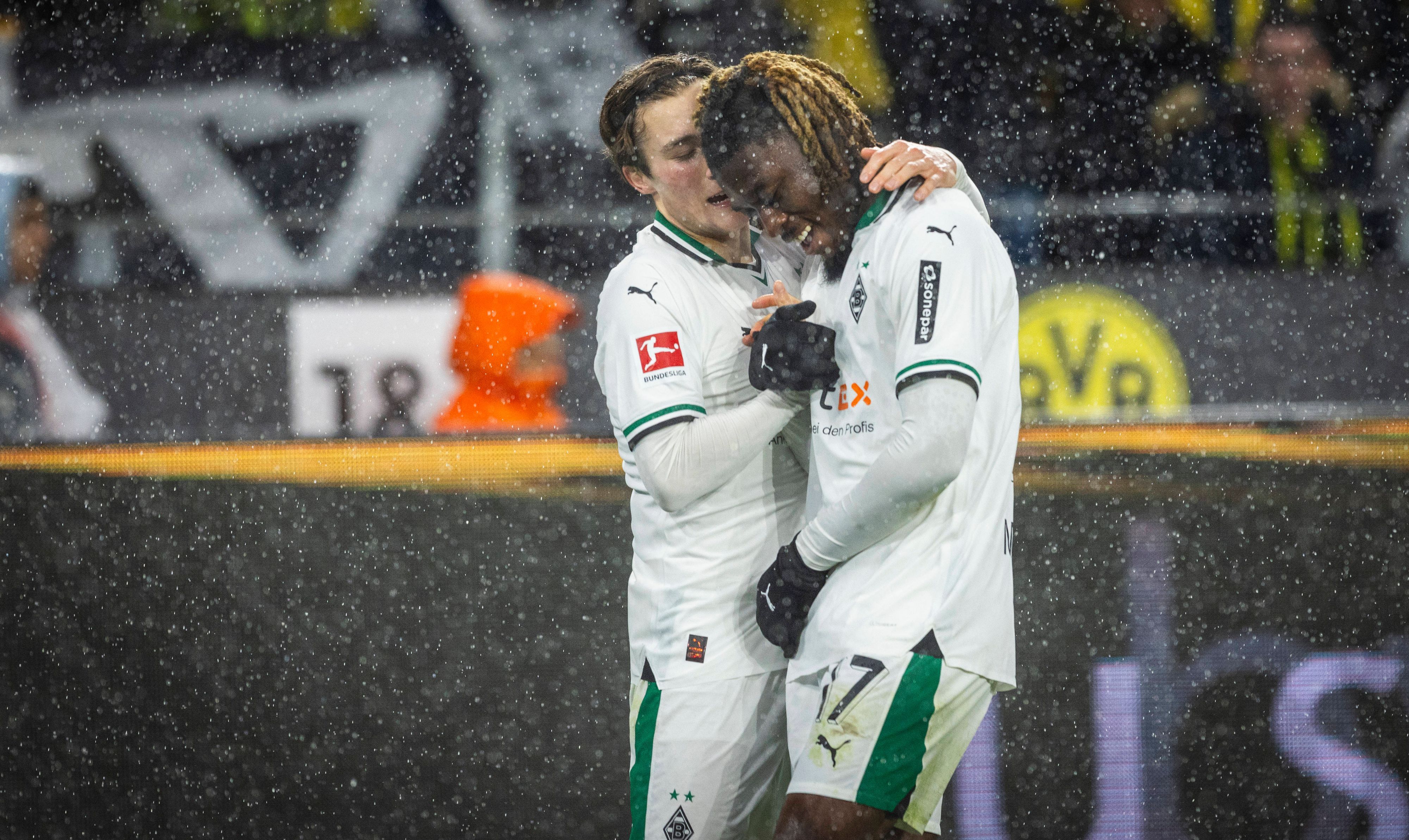 Rocco Reitz und Manu Kone schlagen im Dortmunder Stadion miteinander ein. Es regnet.