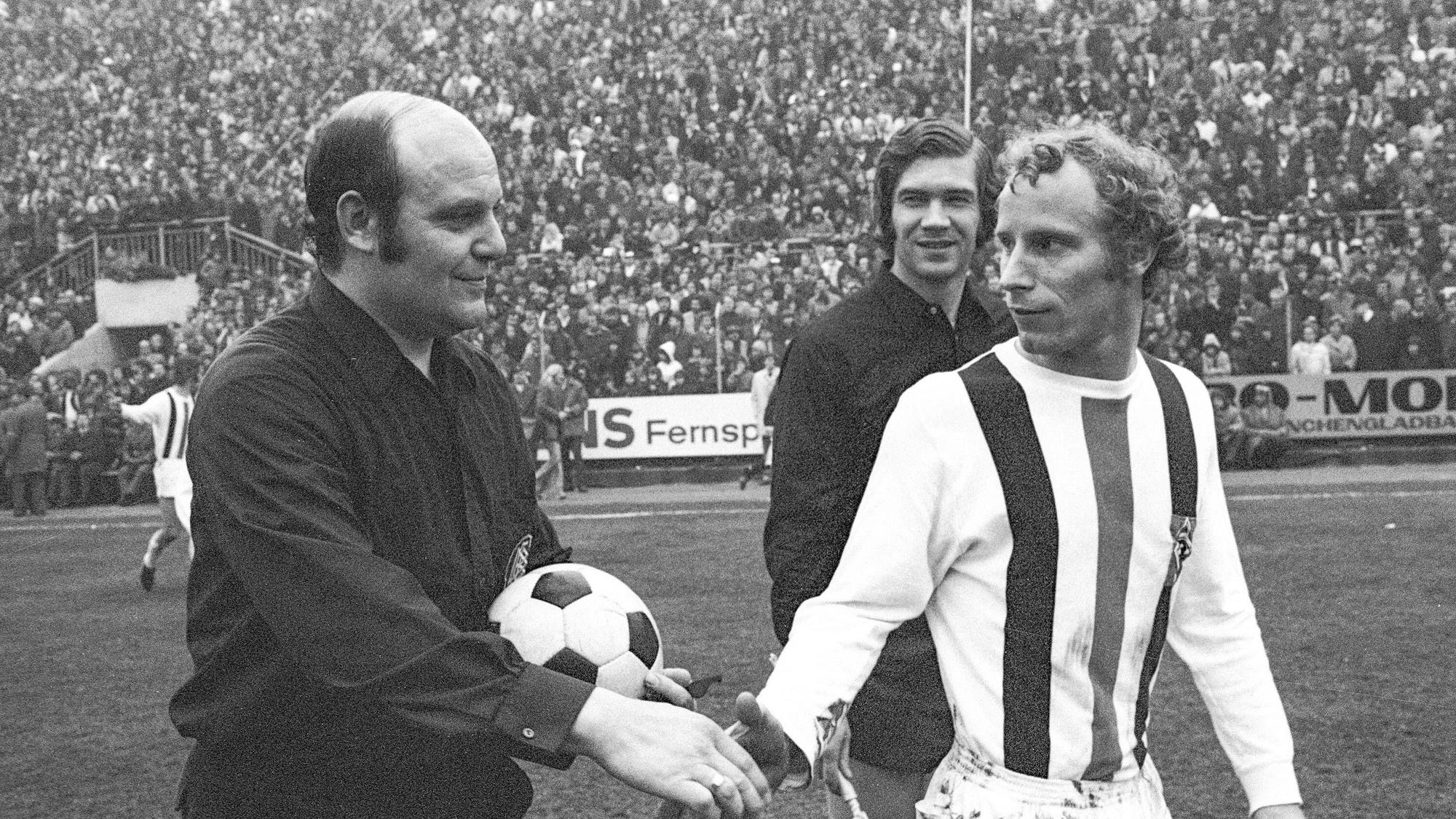 Spieler von Borussia Mönchengladbach gibt Schiedsrichter die Hand.