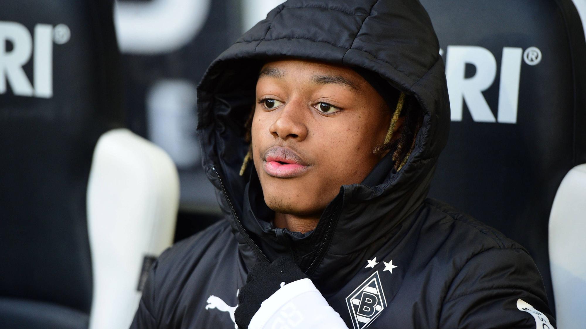Yvandro Borges Sanches sitzt in einer Borussia-Jacke auf der Auswechselbank.
