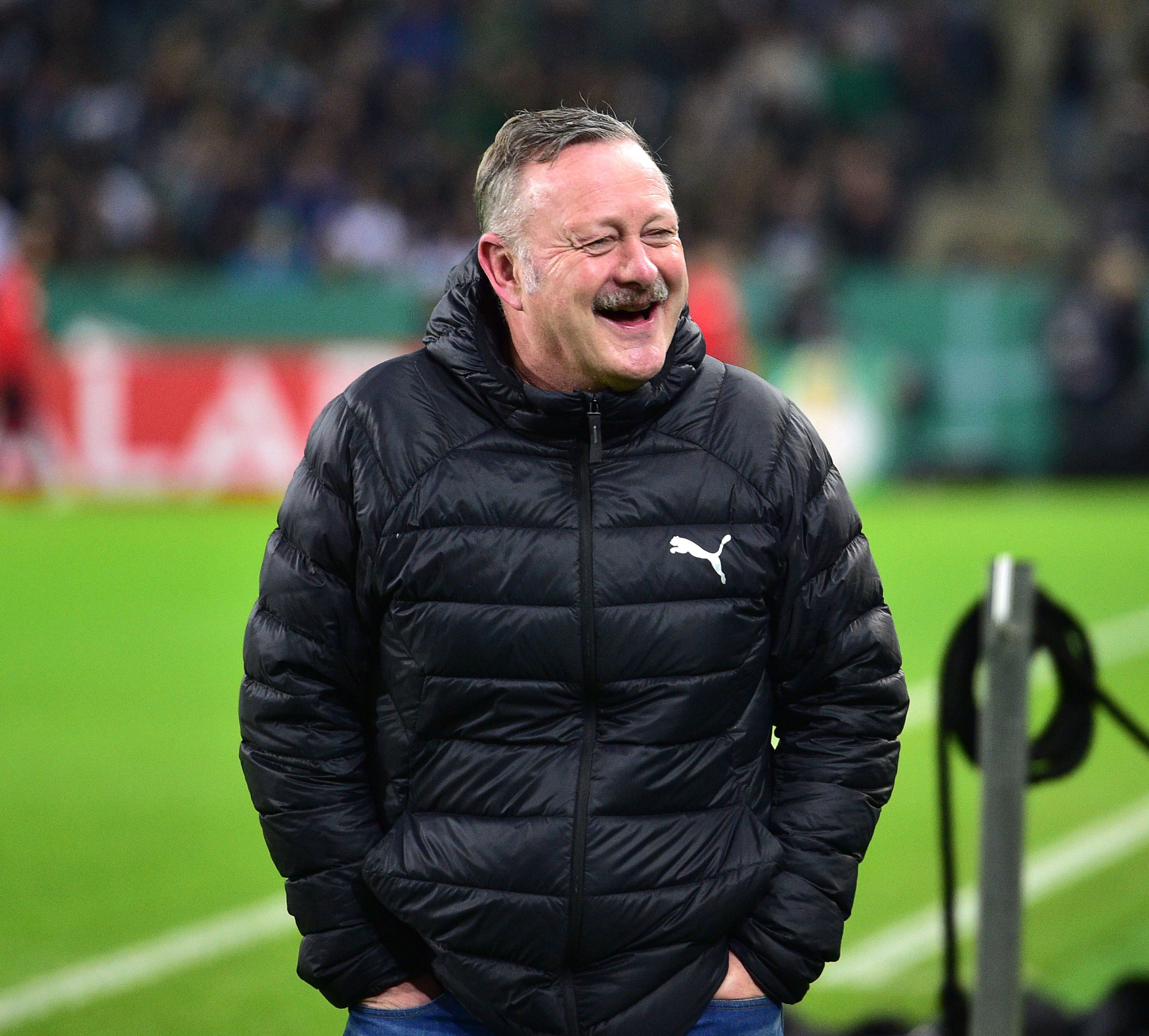Roland Virkus lacht am Spielfeldrand.