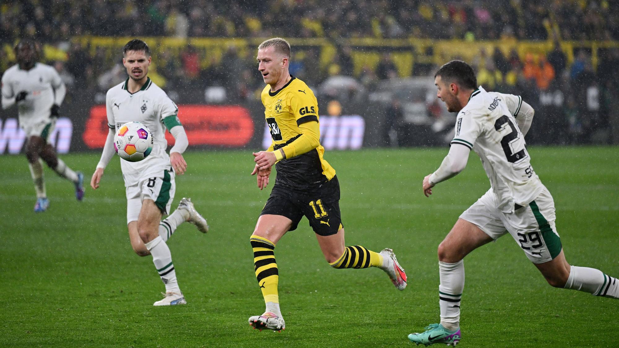 Julian Weigl, Marco Reus und Joe Scally schauen auf den Ball.
