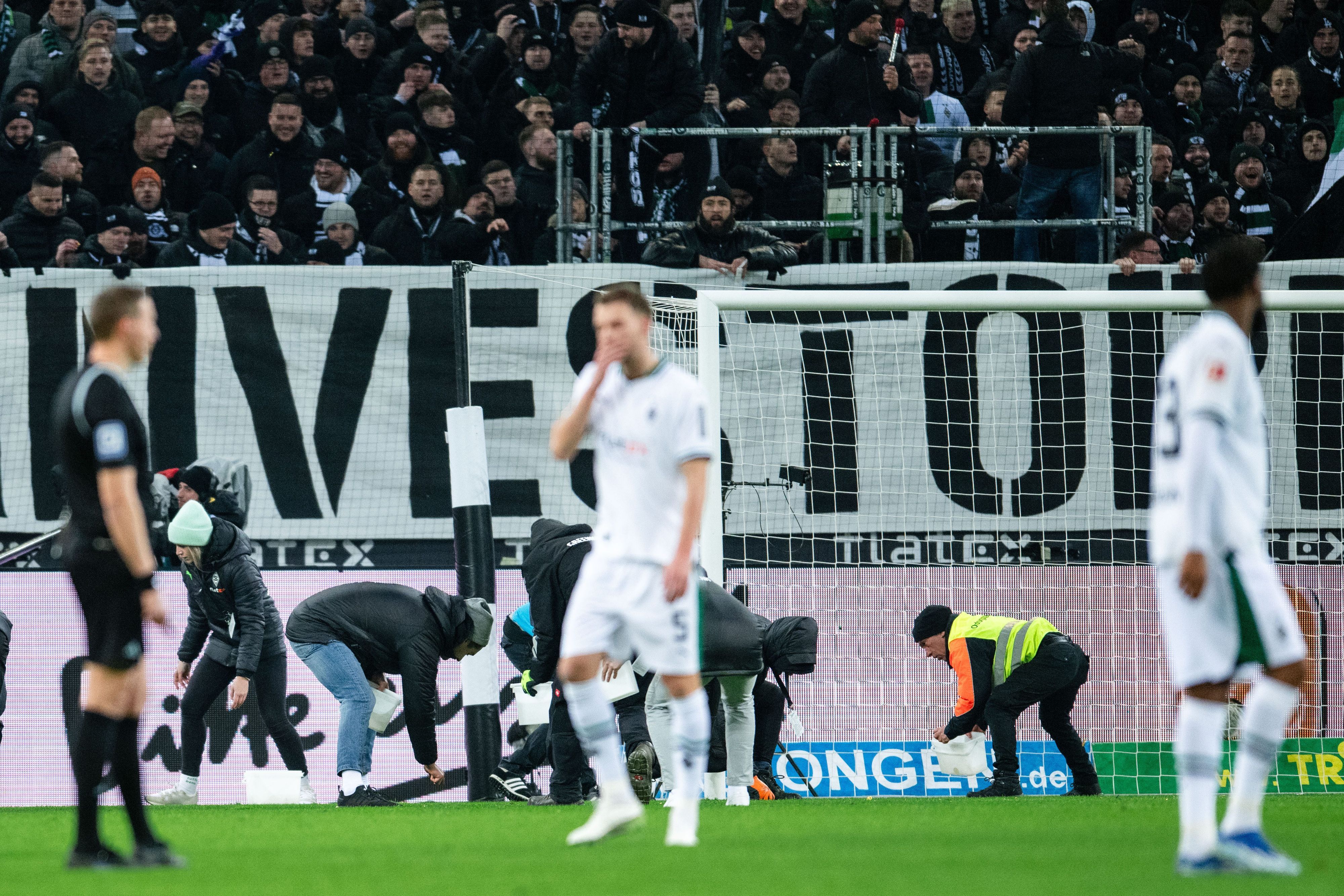 Spieler und Schiedsrichter warten während einer Spielunterbrechung in Gladbach.