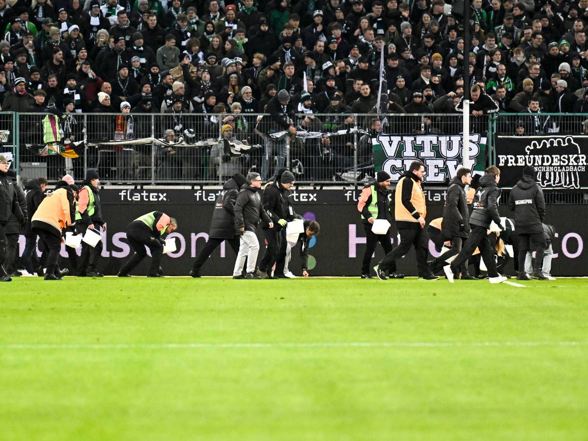 Ordner heben während eines Spiels von Borussia Mönchengladbach Schoko-Taler vom Rasen.