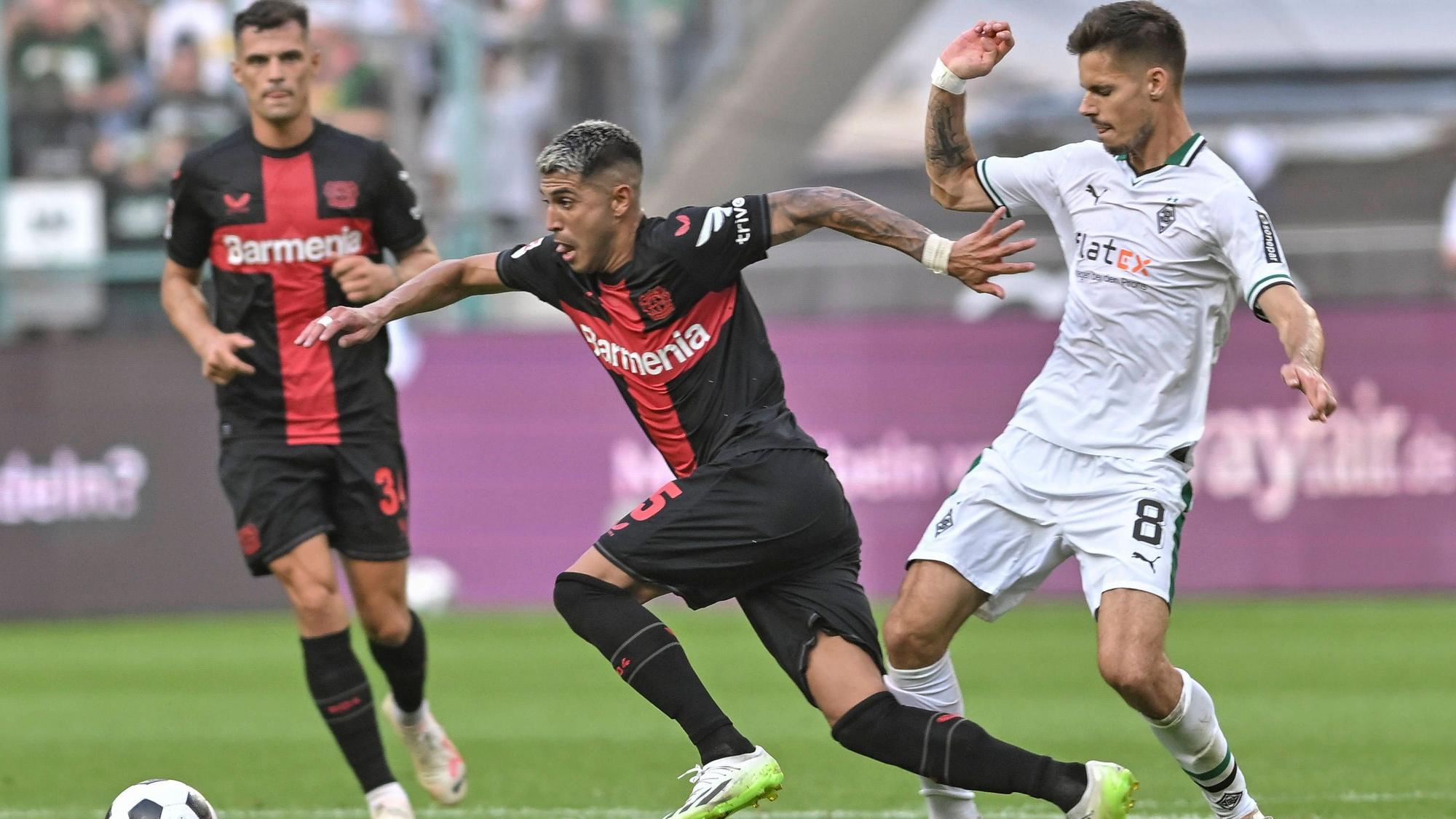 Exequiel Palacios dribbelt, Julian Weigl versucht ihn zu stoppen und trifft ihn am Unterschenkel.