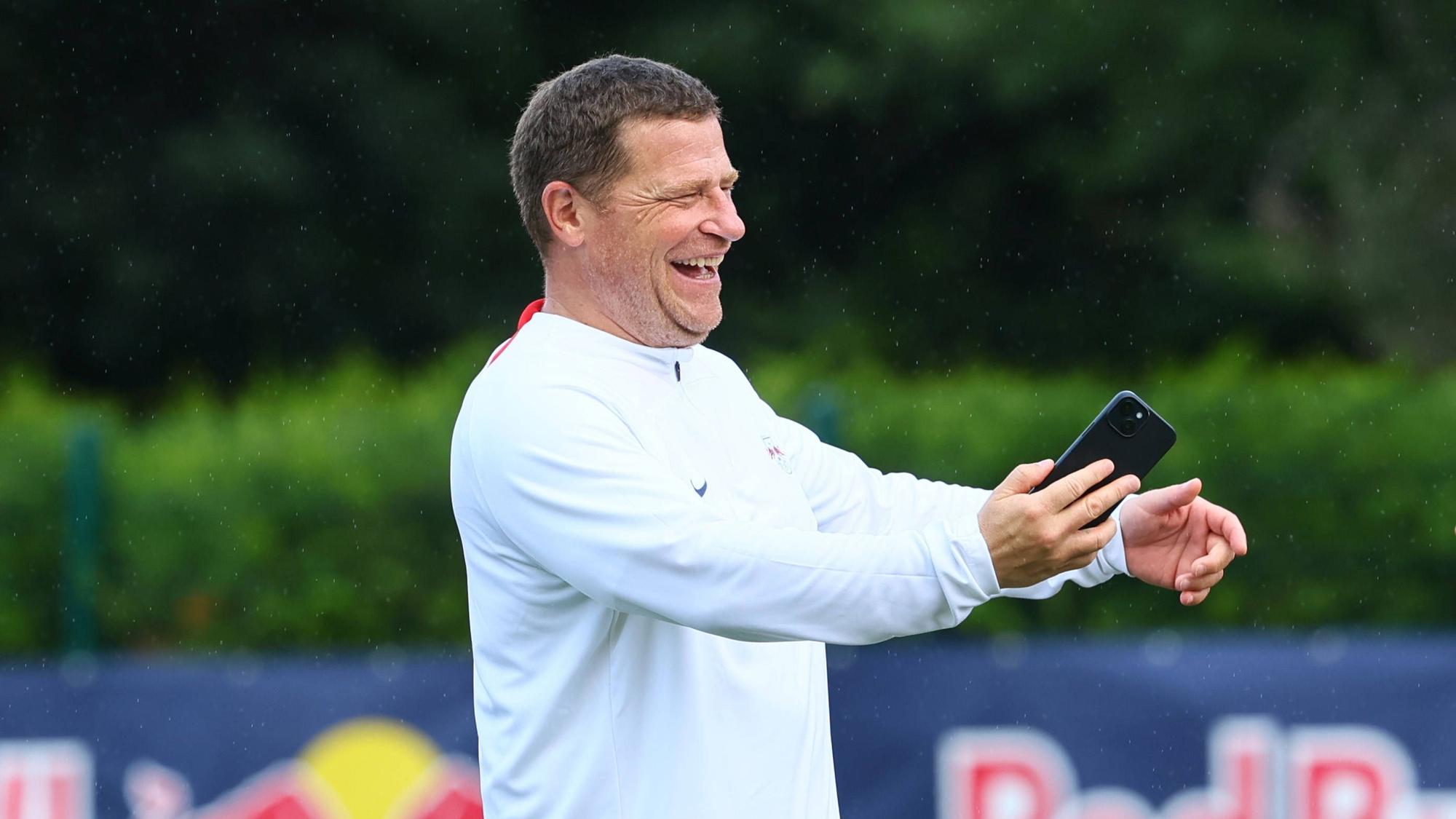 Max Eberl hält ein Handy in der Hand.