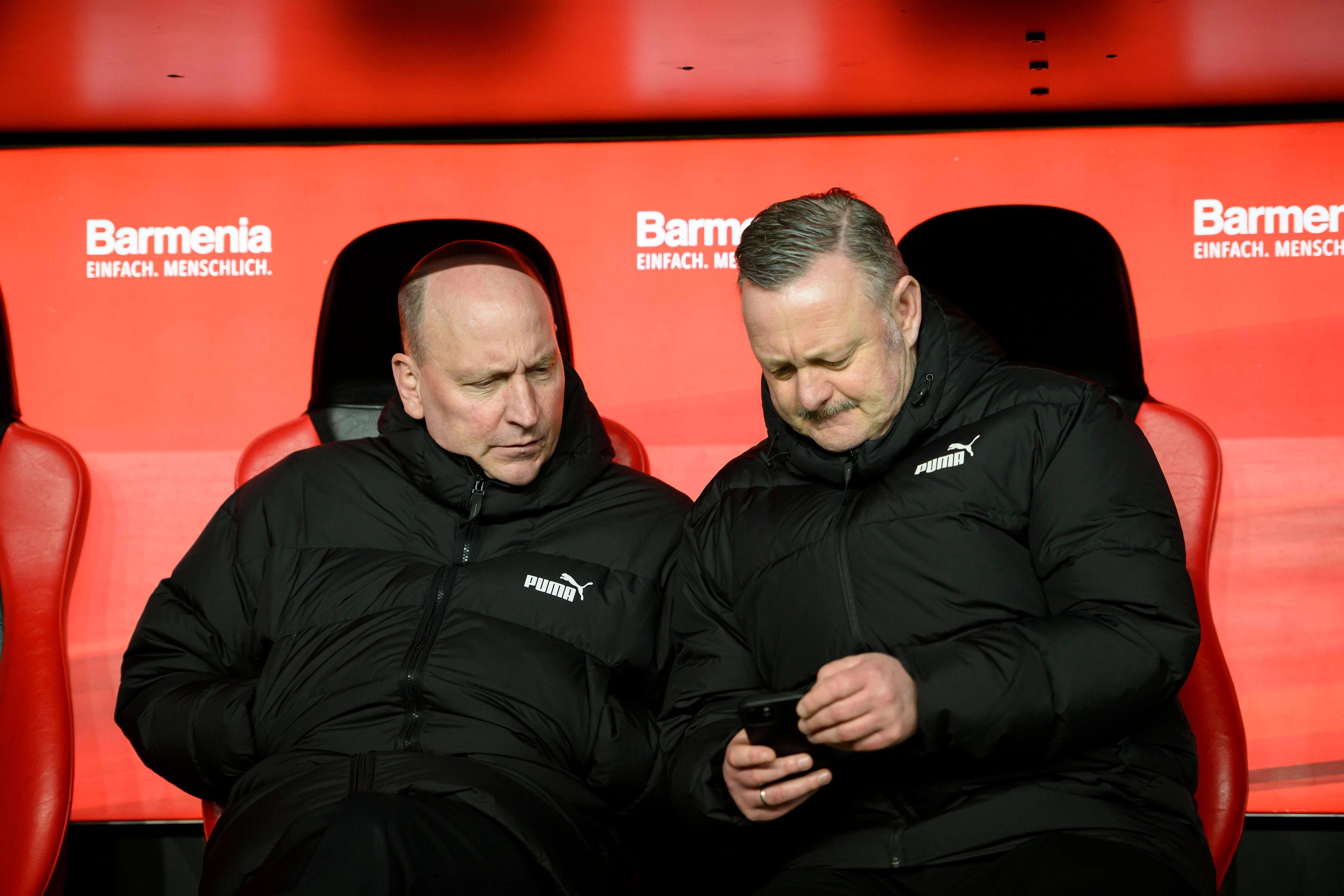 Roland Virkus und Stephan Schippers schauen auf ein Smartphone.