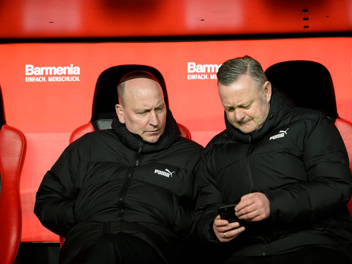 Roland Virkus und Stephan Schippers schauen auf ein Smartphone.