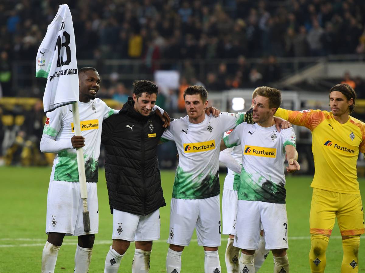 Marcus Thuram hält ein Trikot von Lars Stindl auf einer Eckfahne, Teamkollegen schauen ihm zu.