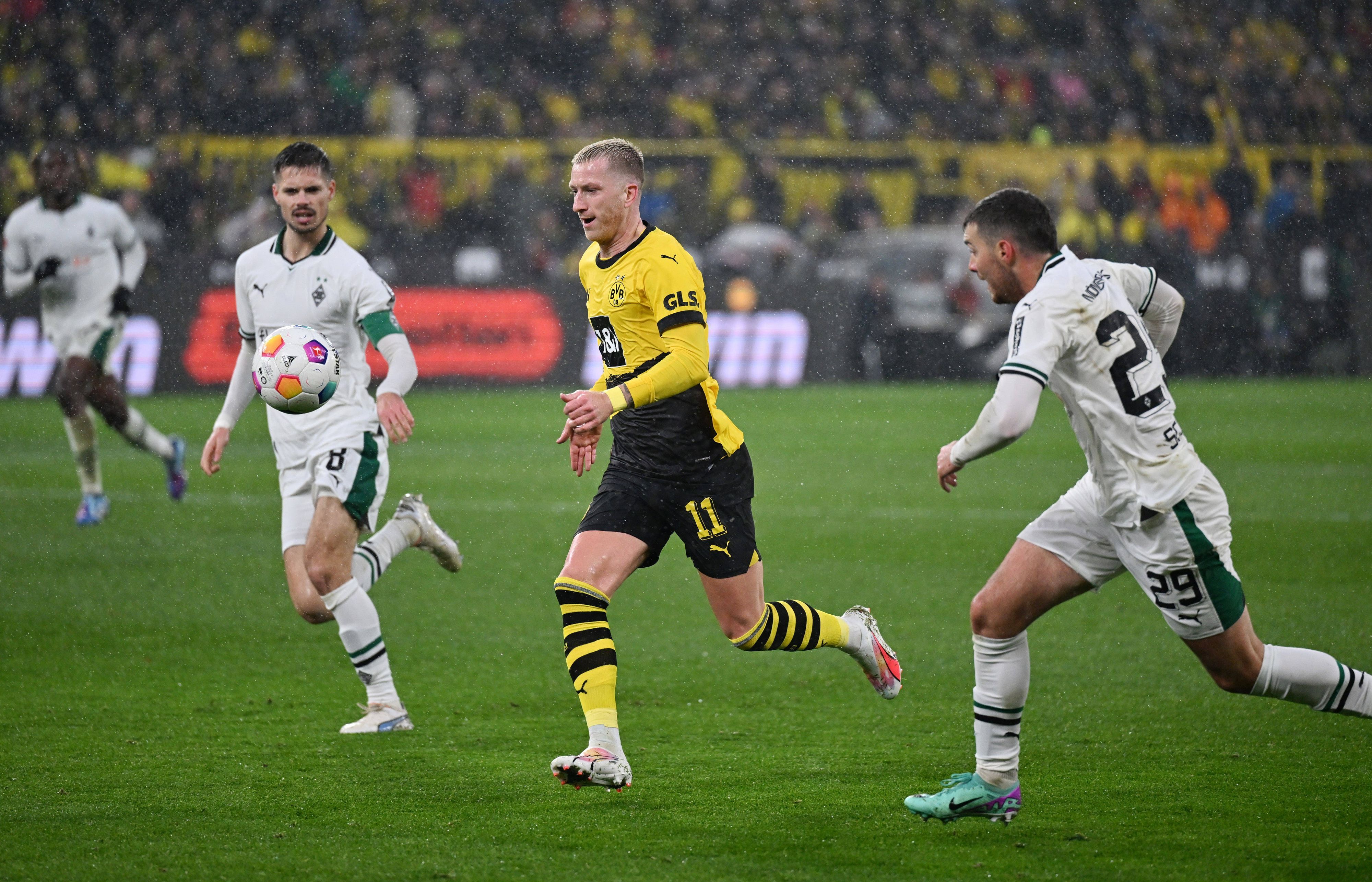 Ein Spieler von Borussia Dortmund setzt sich gegen zwei Spieler von Borussia Mönchengladbach durch.