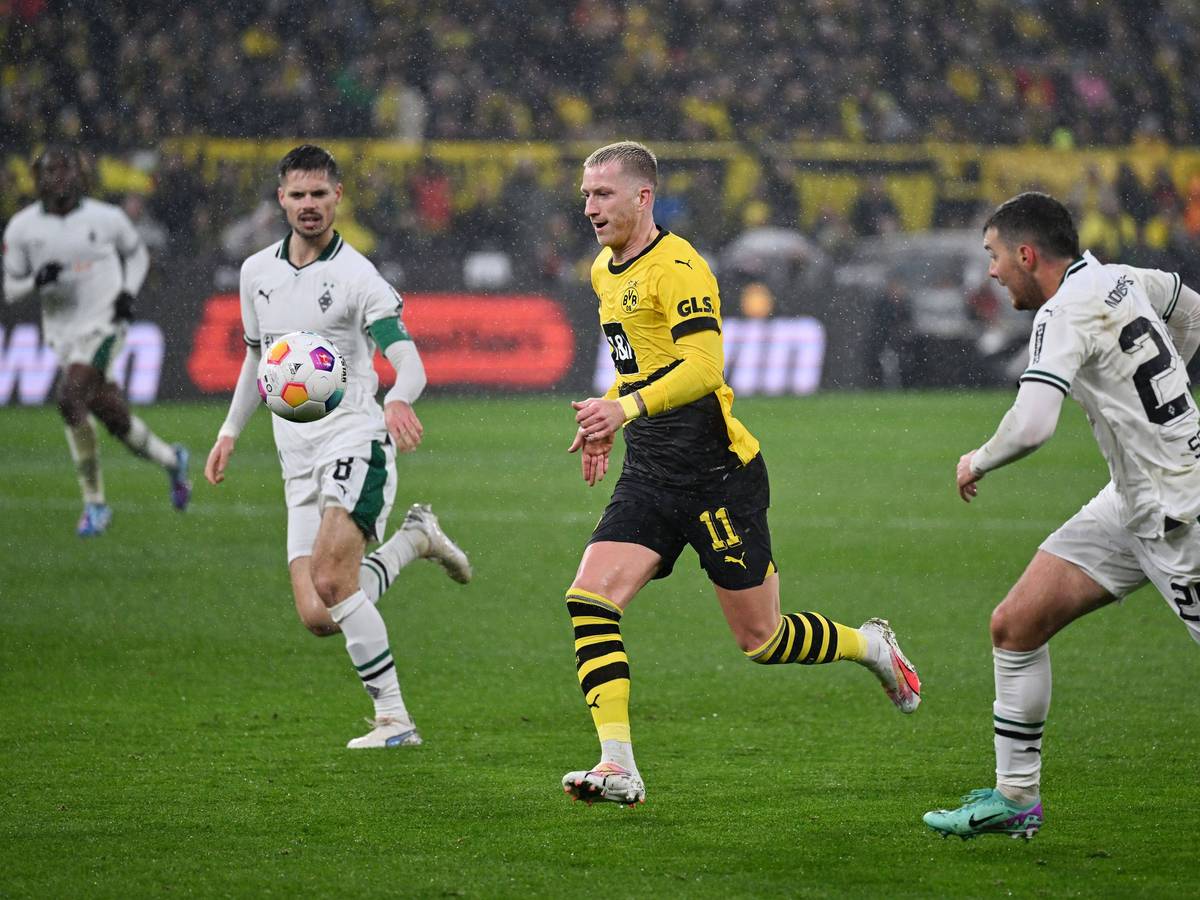 Ein Spieler von Borussia Dortmund setzt sich gegen zwei Spieler von Borussia Mönchengladbach durch.