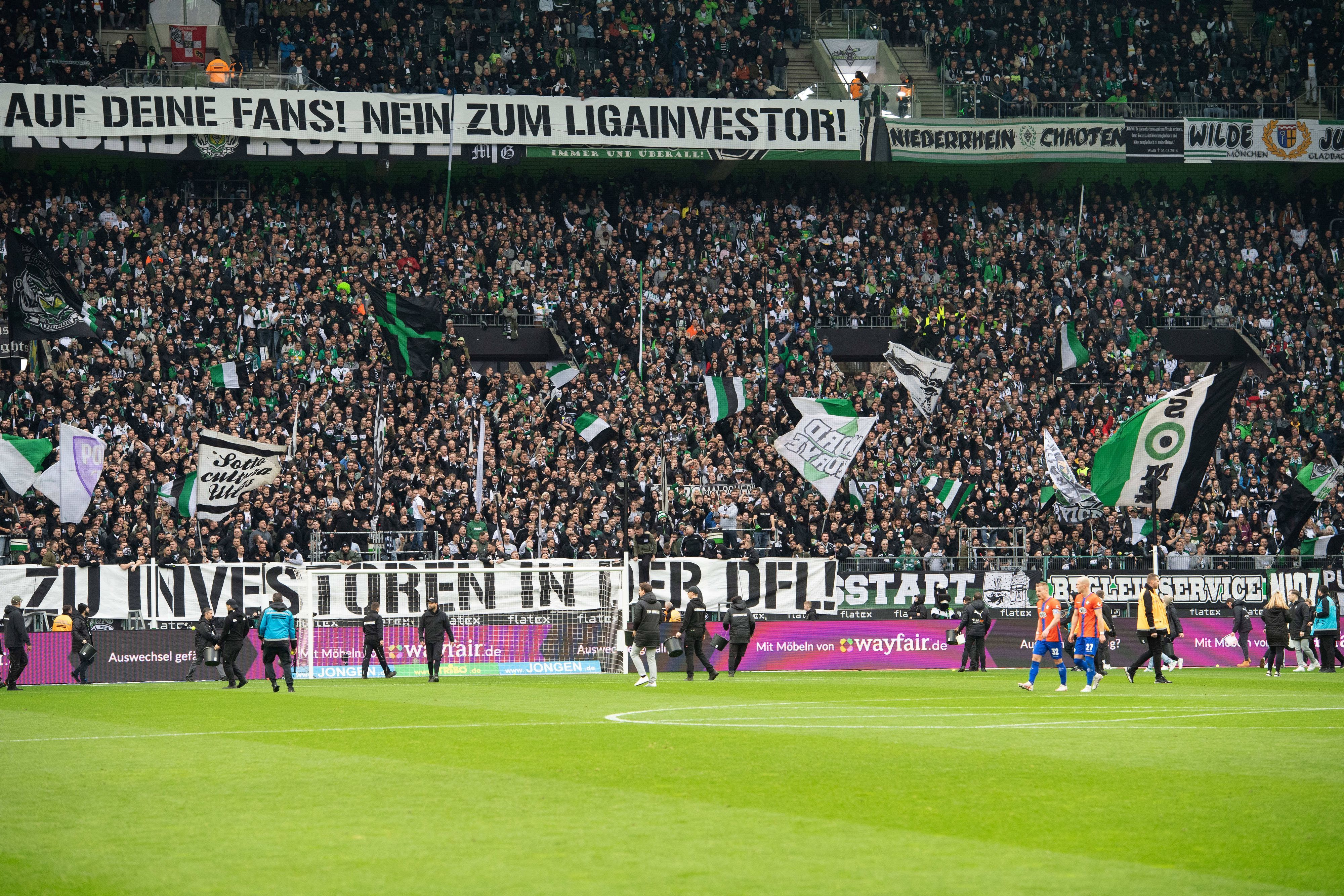 Mitarbeitende sammeln Tennisbälle auf dem Borussia-Park-Rasen ein.