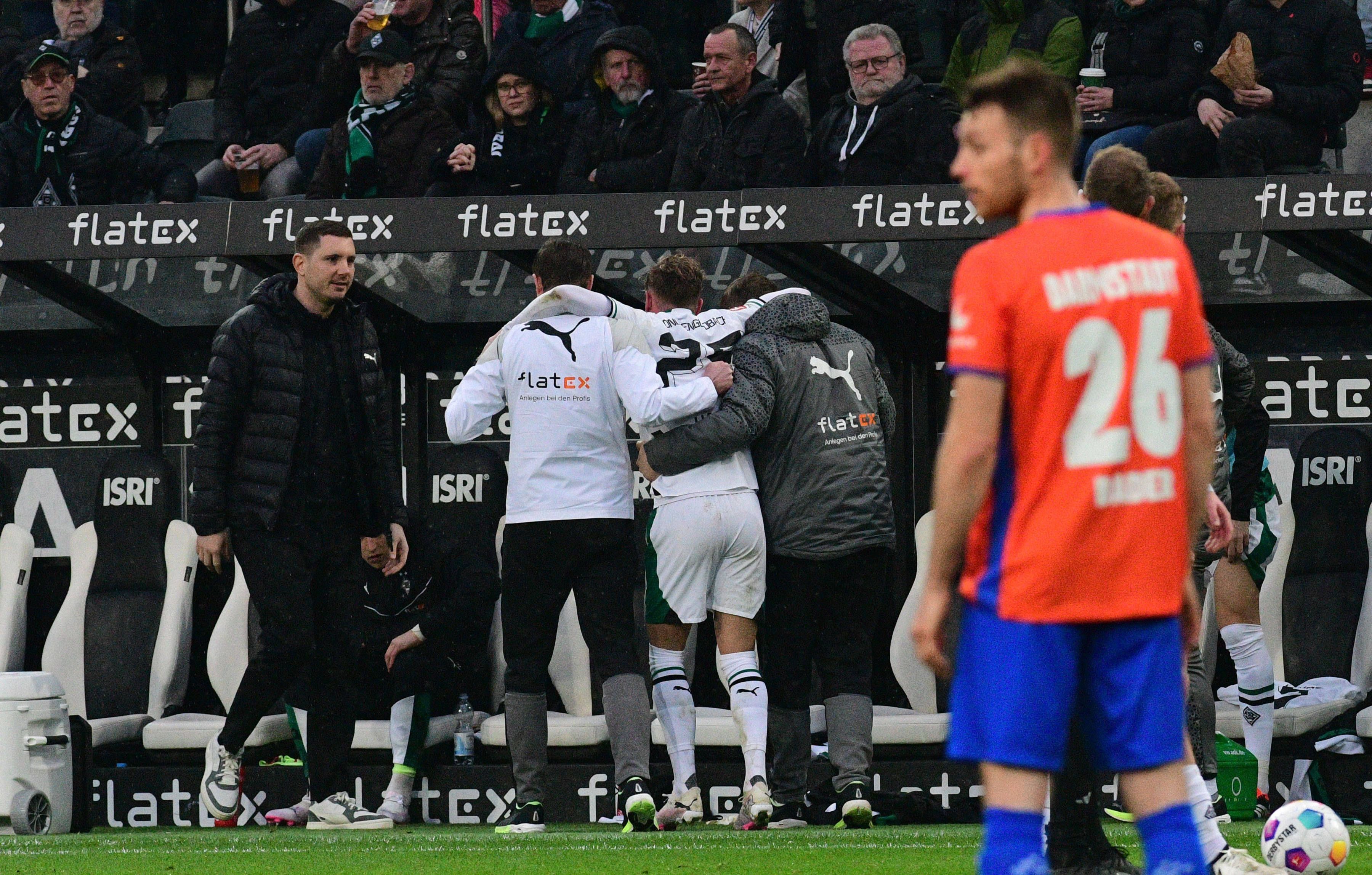 Ein Spieler von Borussia Mönchengladbach wird mithilfe von zwei Medizinern nach einer Verletzung vom Platz geführt.