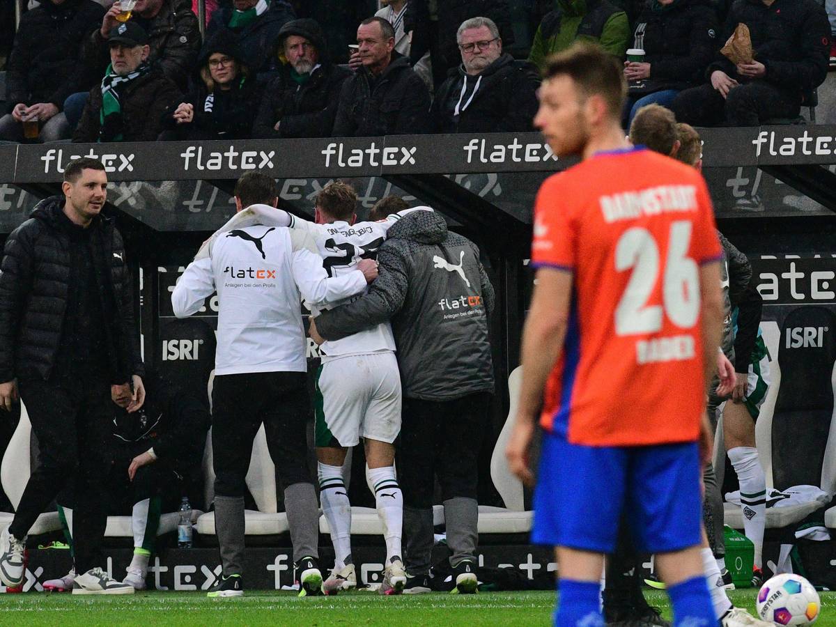 Ein Spieler von Borussia Mönchengladbach wird mithilfe von zwei Medizinern nach einer Verletzung vom Platz geführt.