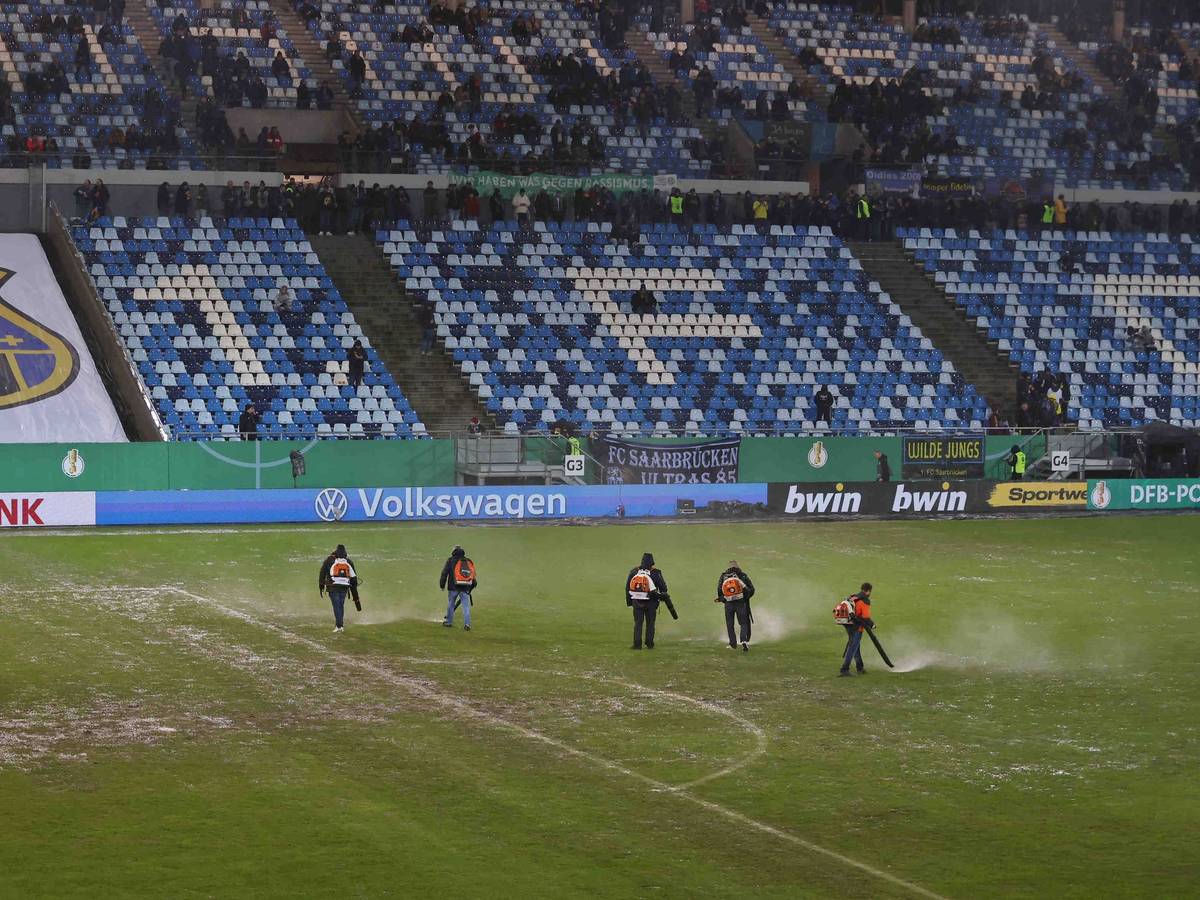 Helferinnen und Helfer mit Laubbläser auf dem Rasen im Ludwigsparkstadion.