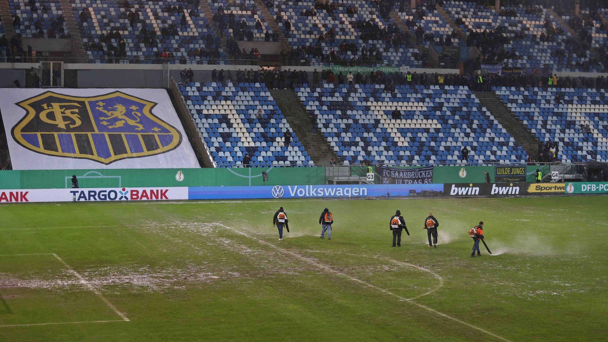 Helferinnen und Helfer mit Laubbläser auf dem Rasen im Ludwigsparkstadion.