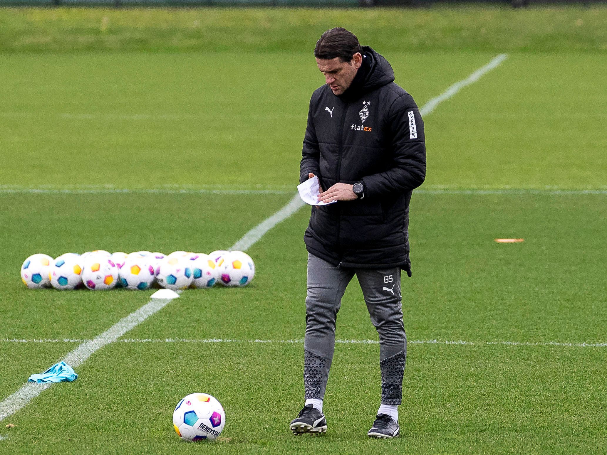 Trainer von Borussia Mönchengladbach während des Trainings mit einem Zettel in der Hand.