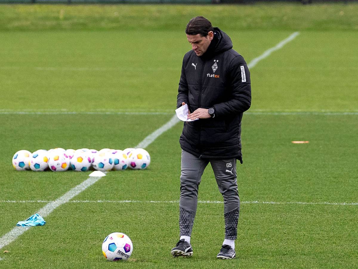 Trainer von Borussia Mönchengladbach während des Trainings mit einem Zettel in der Hand.