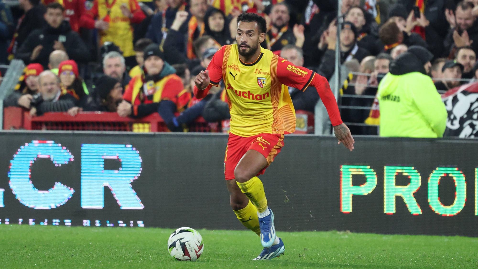 Angelo Fulgini dribbelt mit dem Ball im gelben Lens-Trikot.