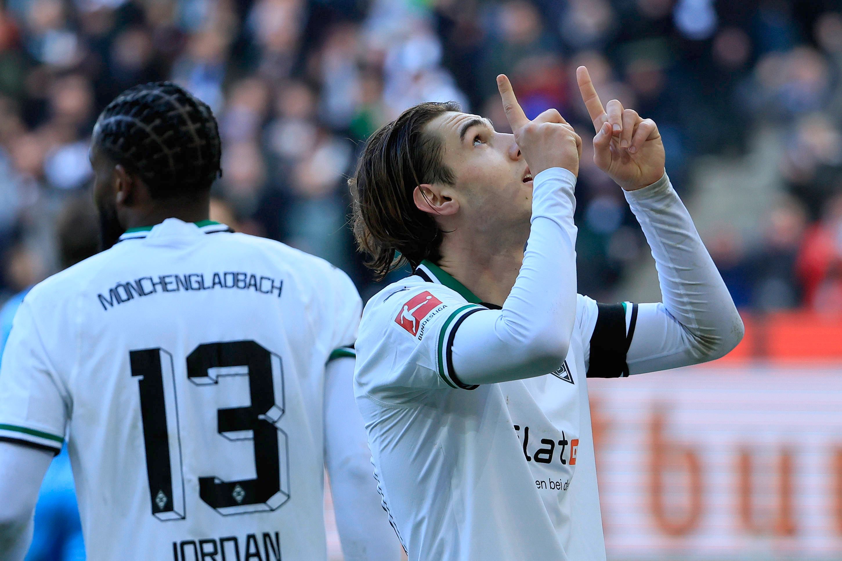 Flo Neuhaus zeigt mit zwei Fingern in die Luft.