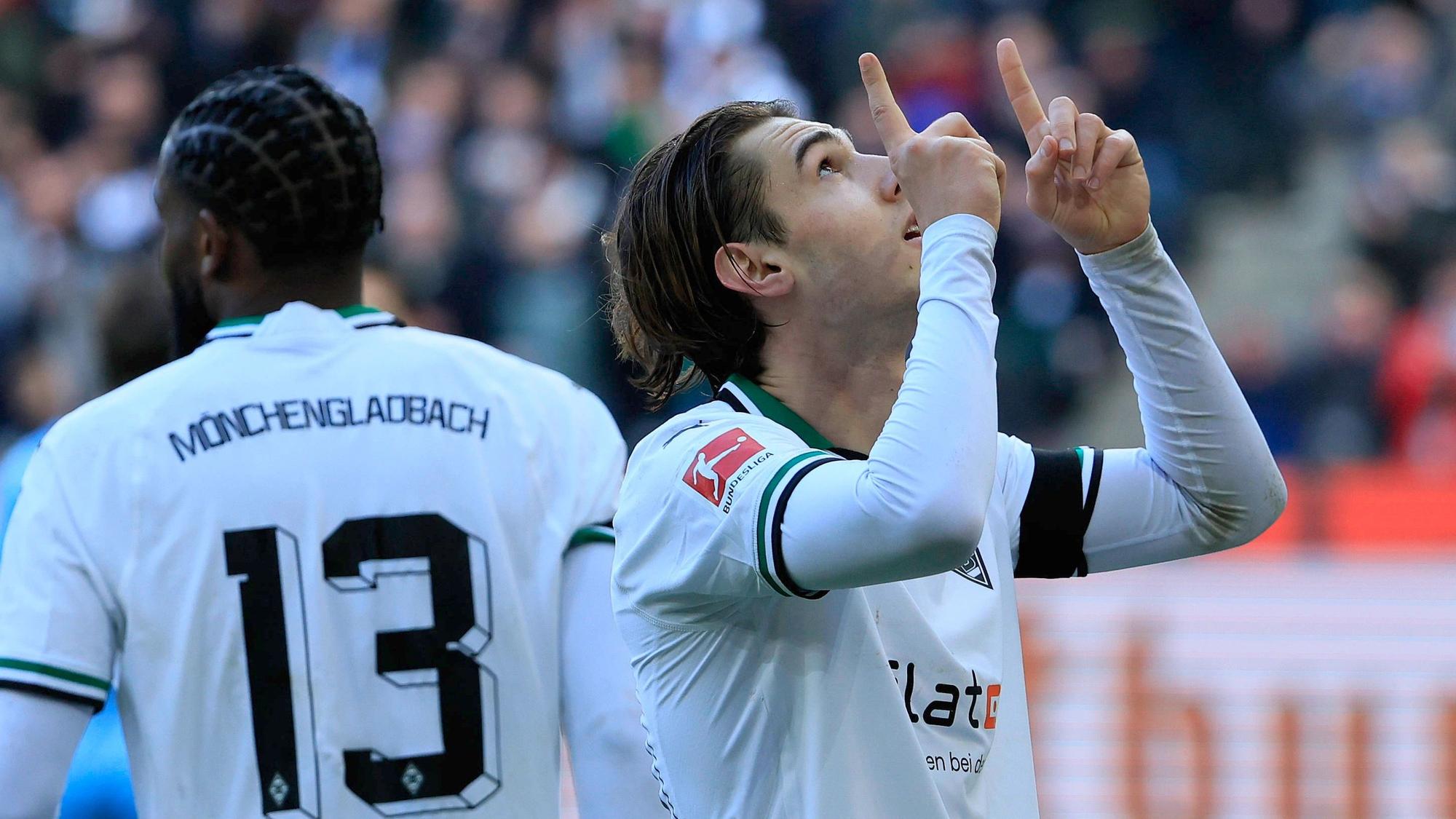 Flo Neuhaus zeigt mit zwei Fingern in die Luft.