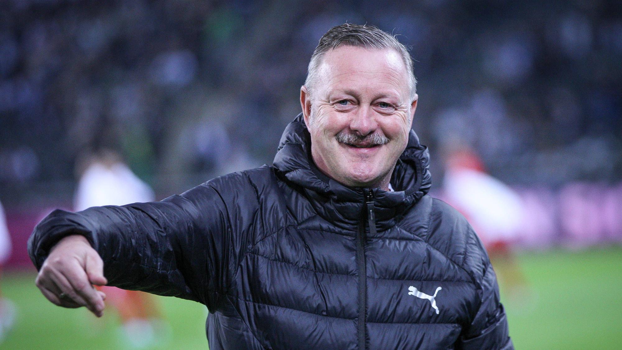 Roland Virkus grinst am Spielfeldrand.