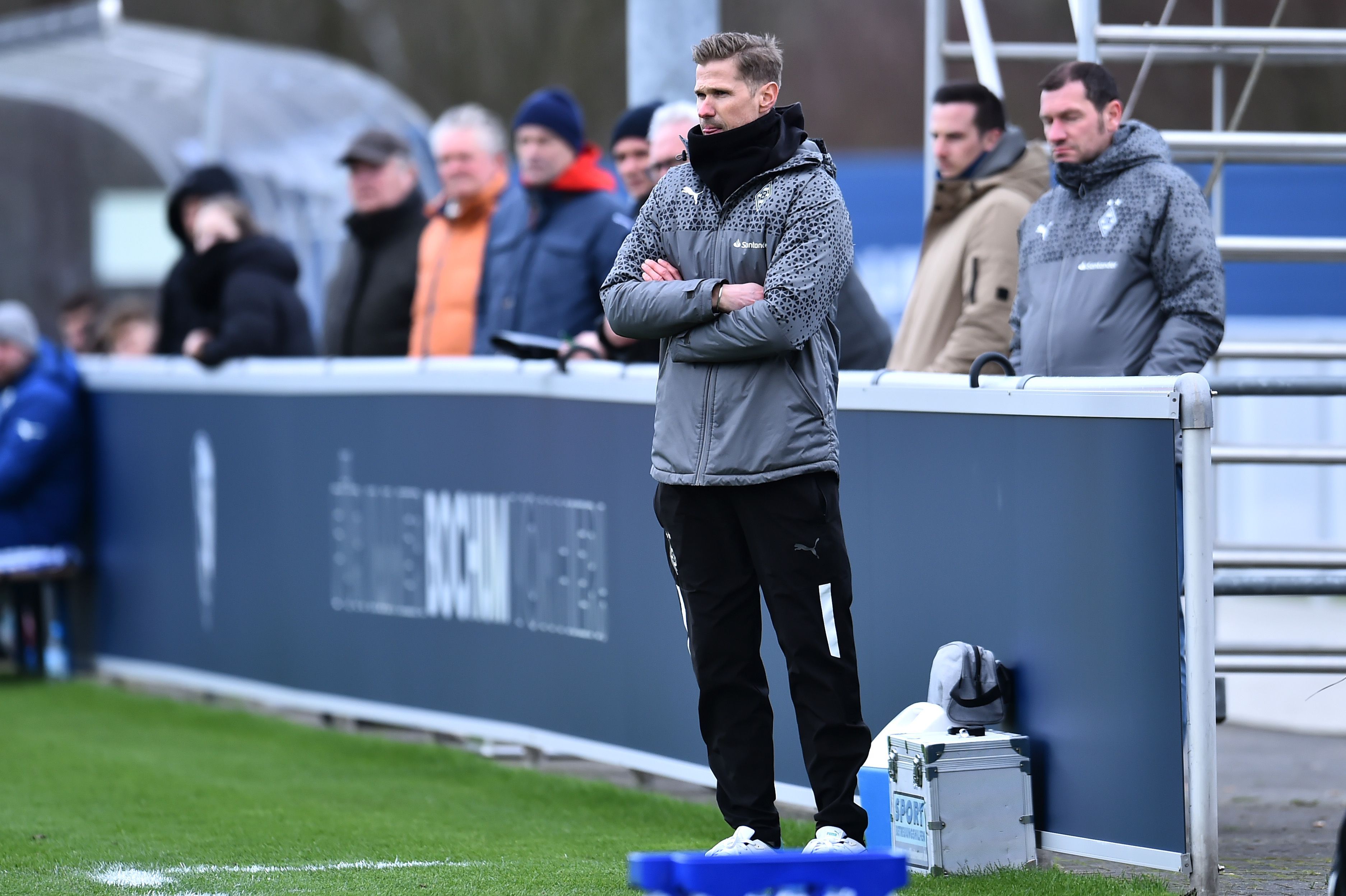 Trainer der U19 von Borussia Mönchengladbach verschränkt die Arme in der Coaching-Zone.