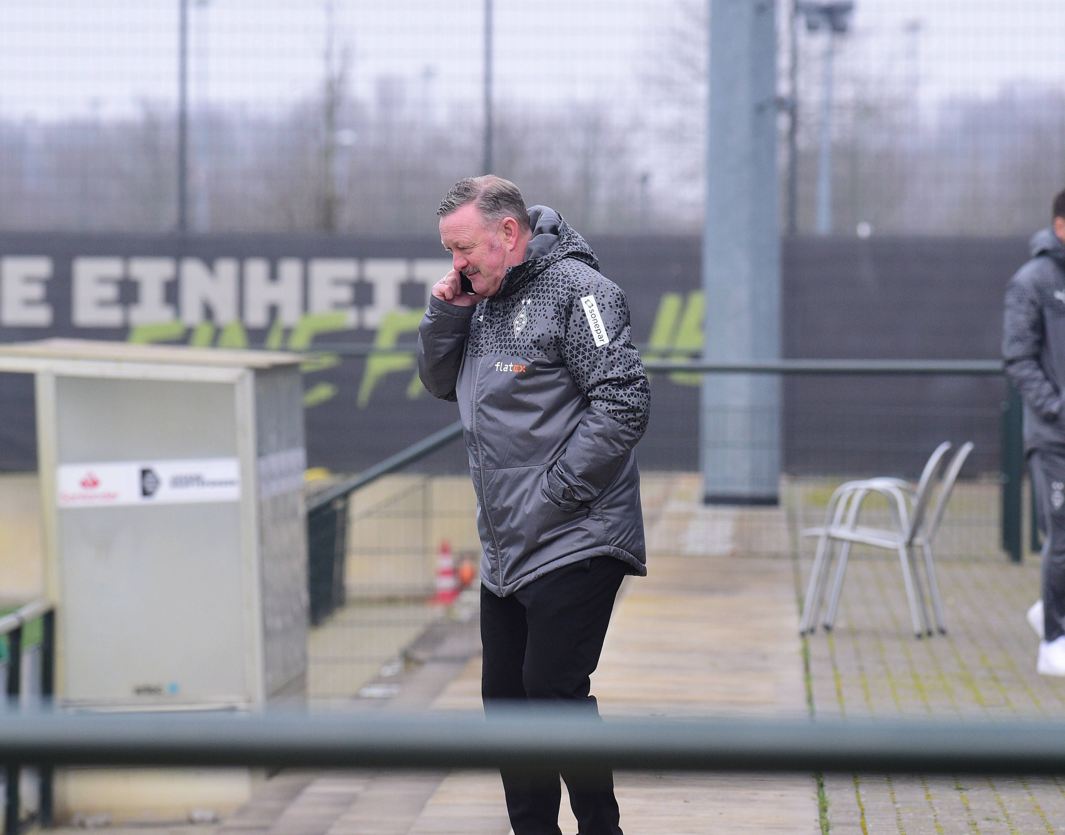 Sport-Chef von Borussia Mönchengladbach mit Telefon am Ohr beim Training.