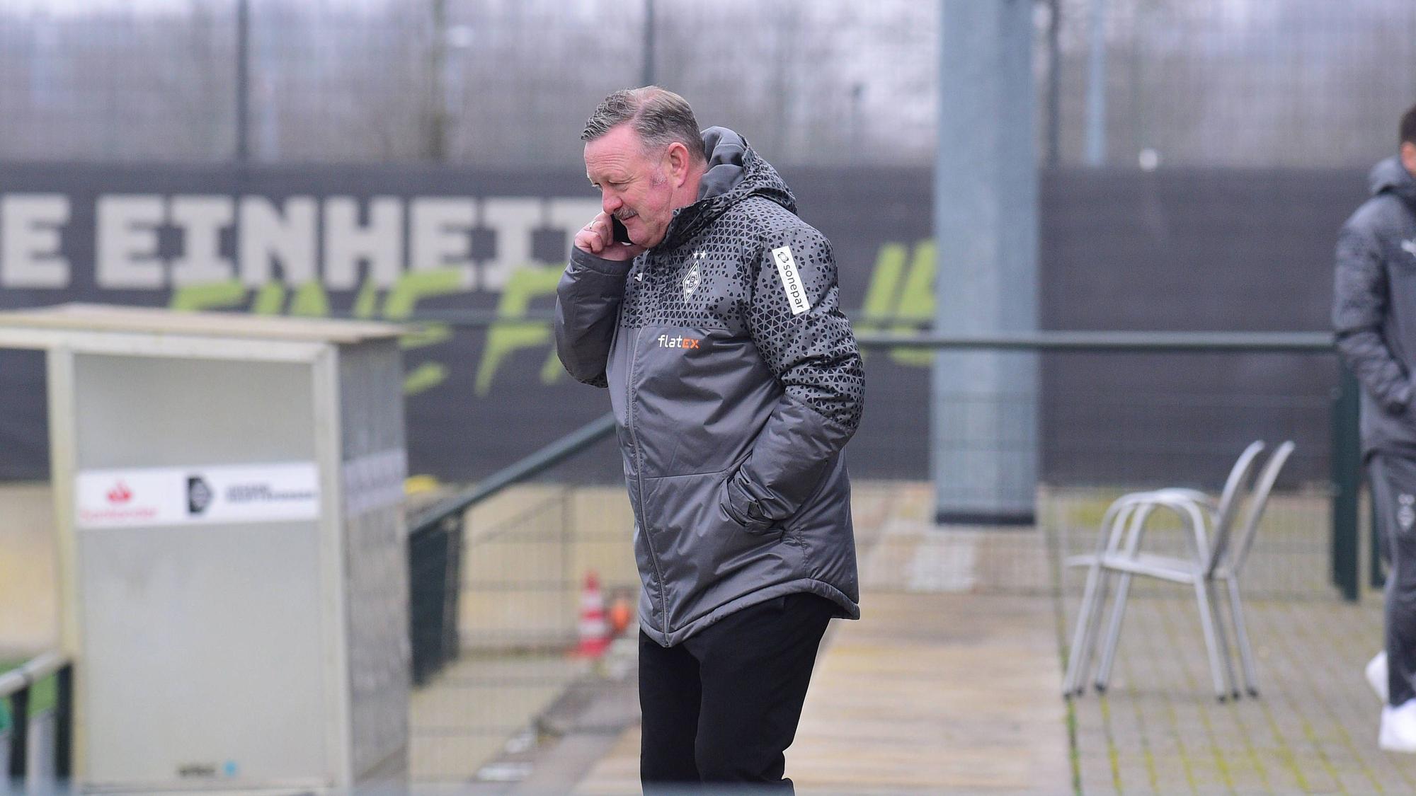 Sport-Chef von Borussia Mönchengladbach mit Telefon am Ohr beim Training.