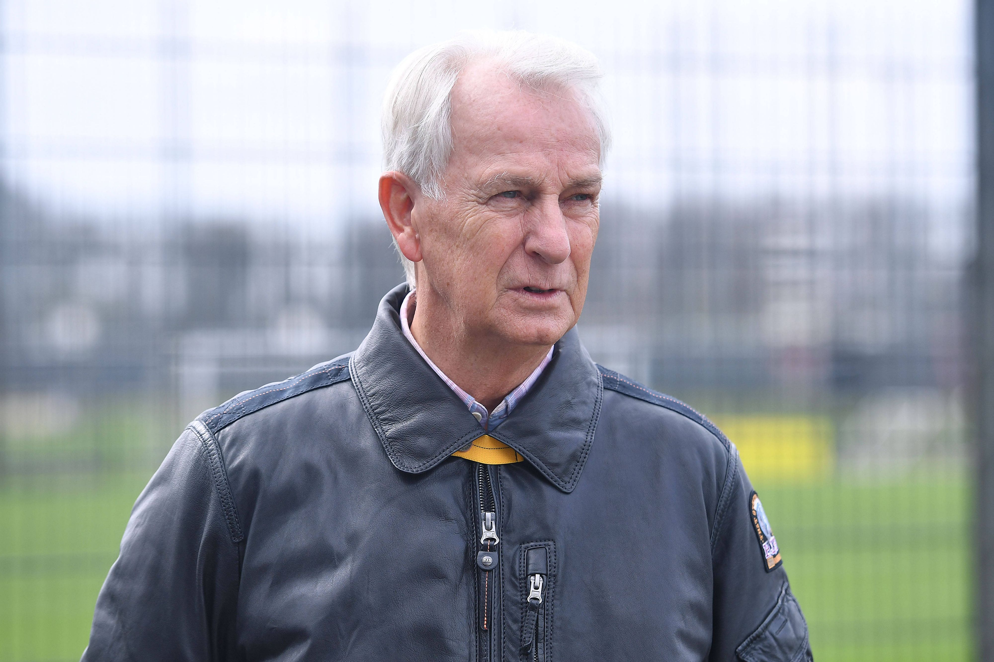 Rainer Bonhof mit fokussiertem Blick in einer Lederjacke am Trainingsplatz.