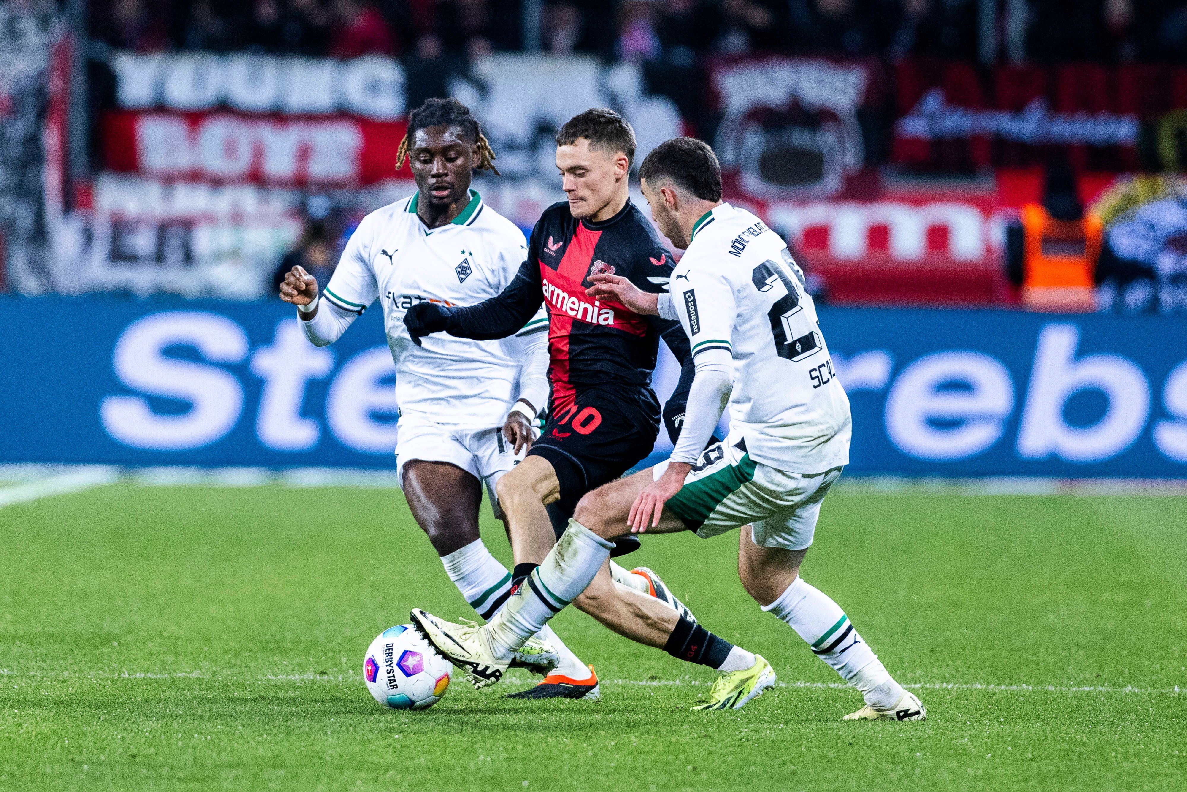 Florian Wirtz behauptet den Ball gegen zwei Spieler von Borussia Mönchengladbach.