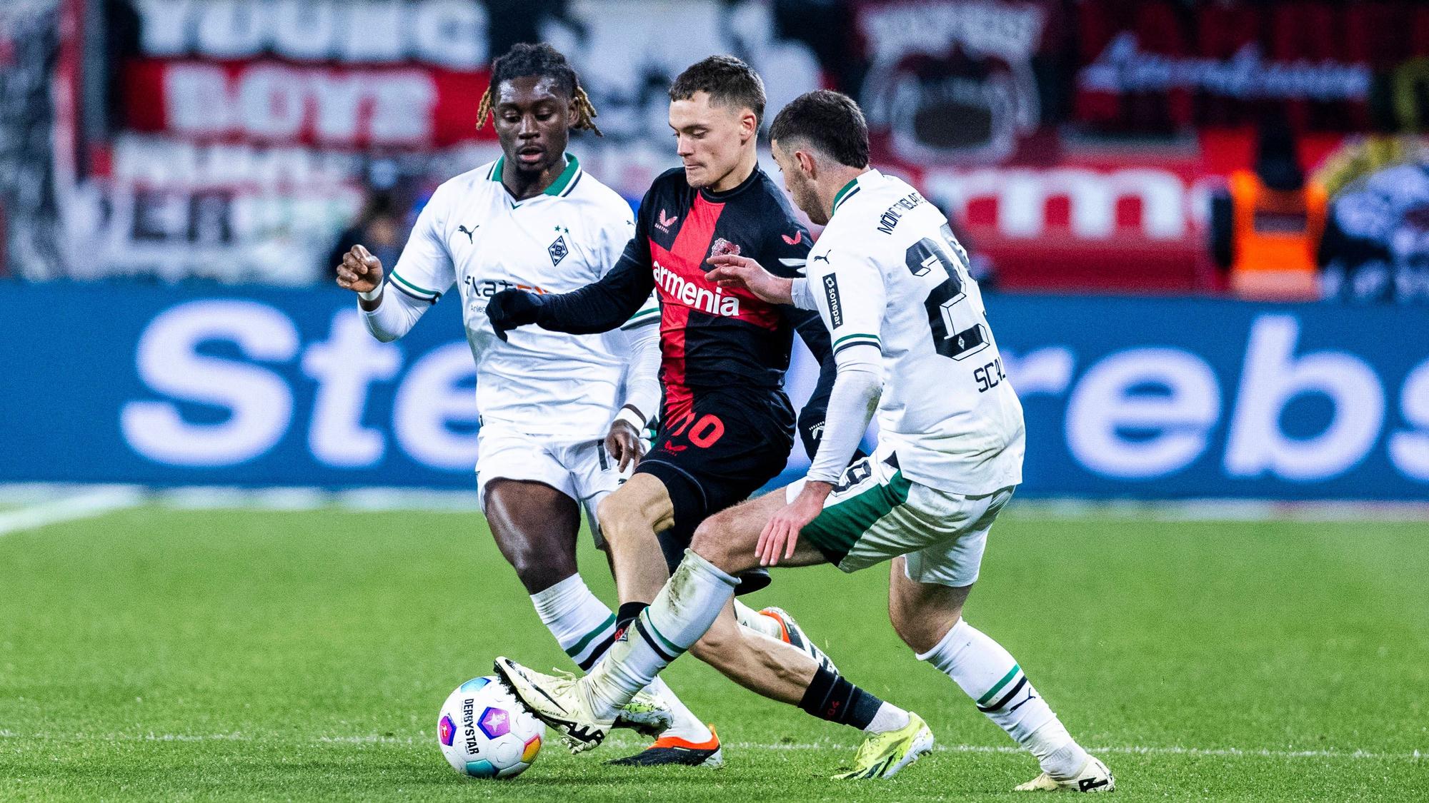 Florian Wirtz behauptet den Ball gegen zwei Spieler von Borussia Mönchengladbach.