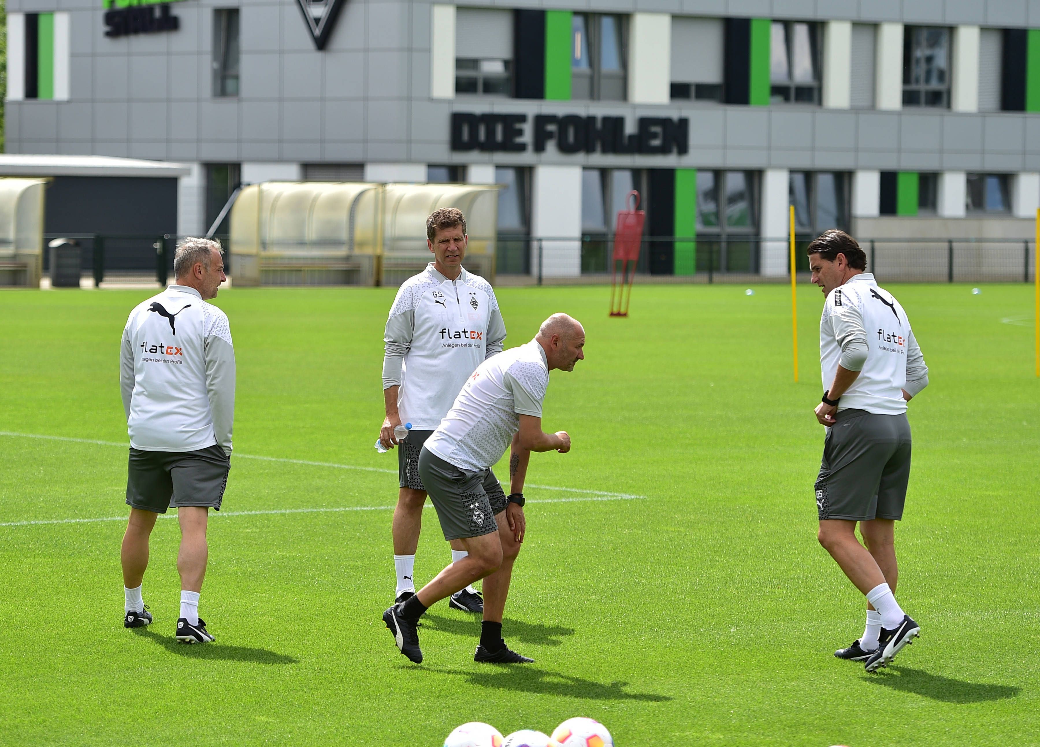 Vier Gladbach-Trainer auf dem Platz. Oliver Neuville greift sich ans Knie.