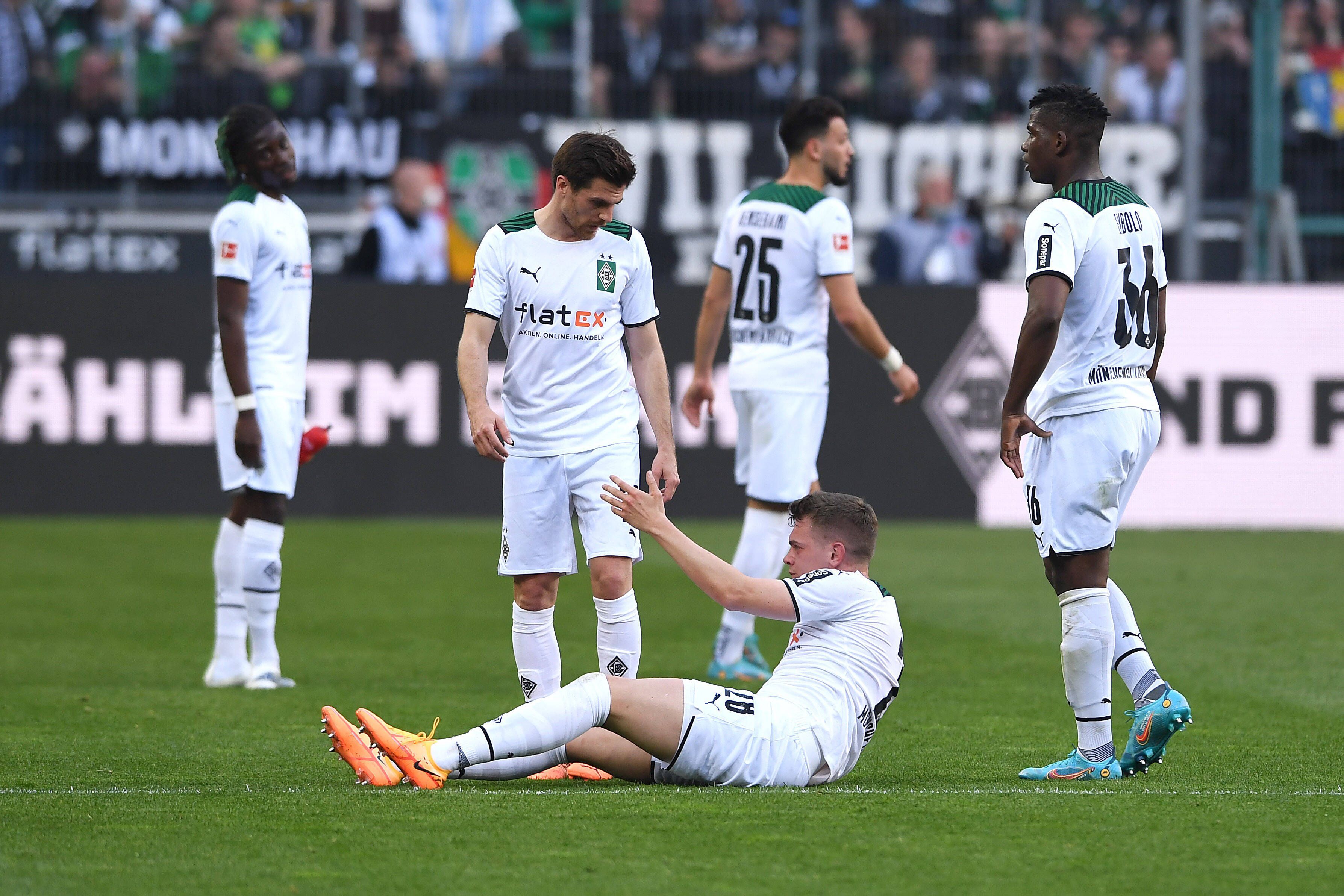 Spieler von Borussia Mönchengladbach hilft seinem Team-Kollegen auf.