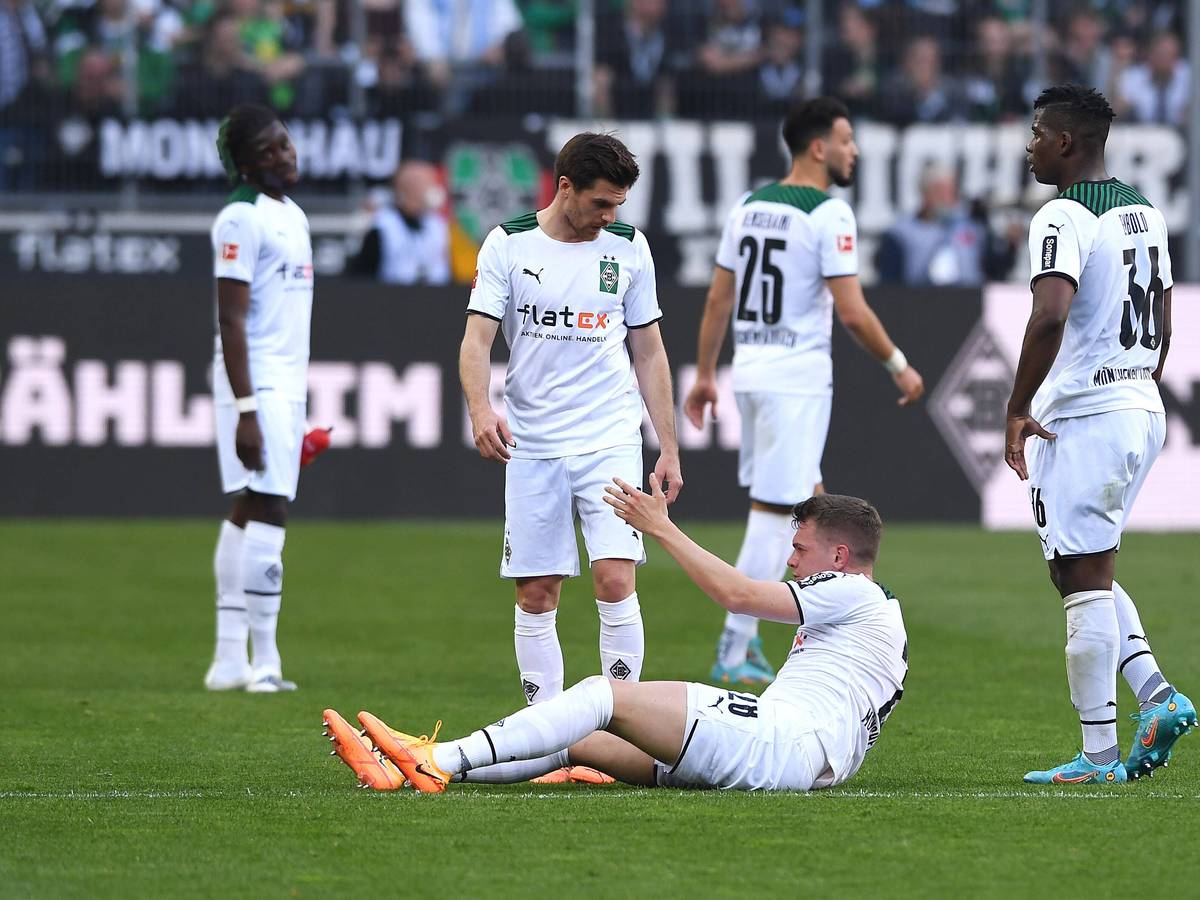 Spieler von Borussia Mönchengladbach hilft seinem Team-Kollegen auf.
