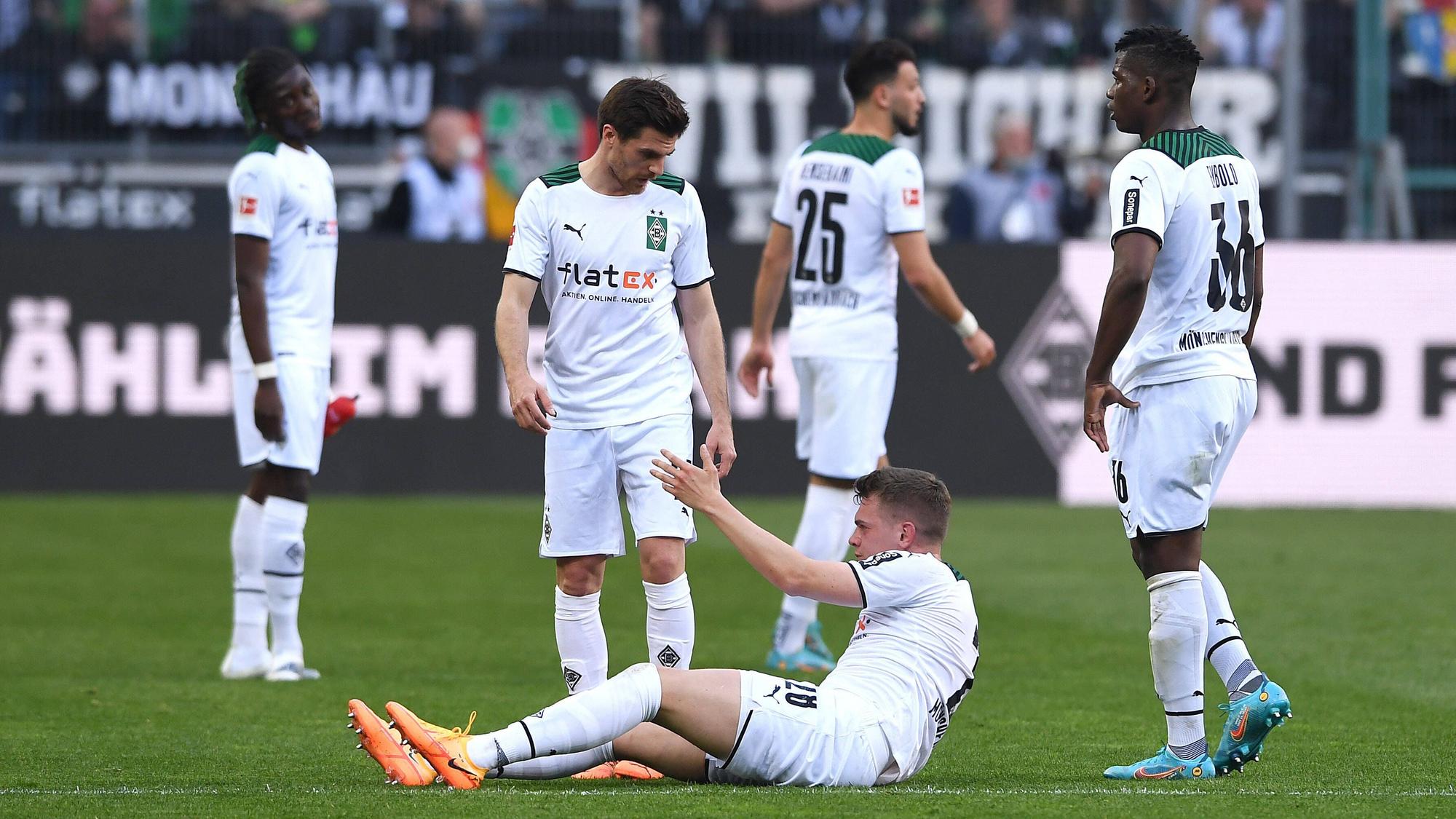 Spieler von Borussia Mönchengladbach hilft seinem Team-Kollegen auf.