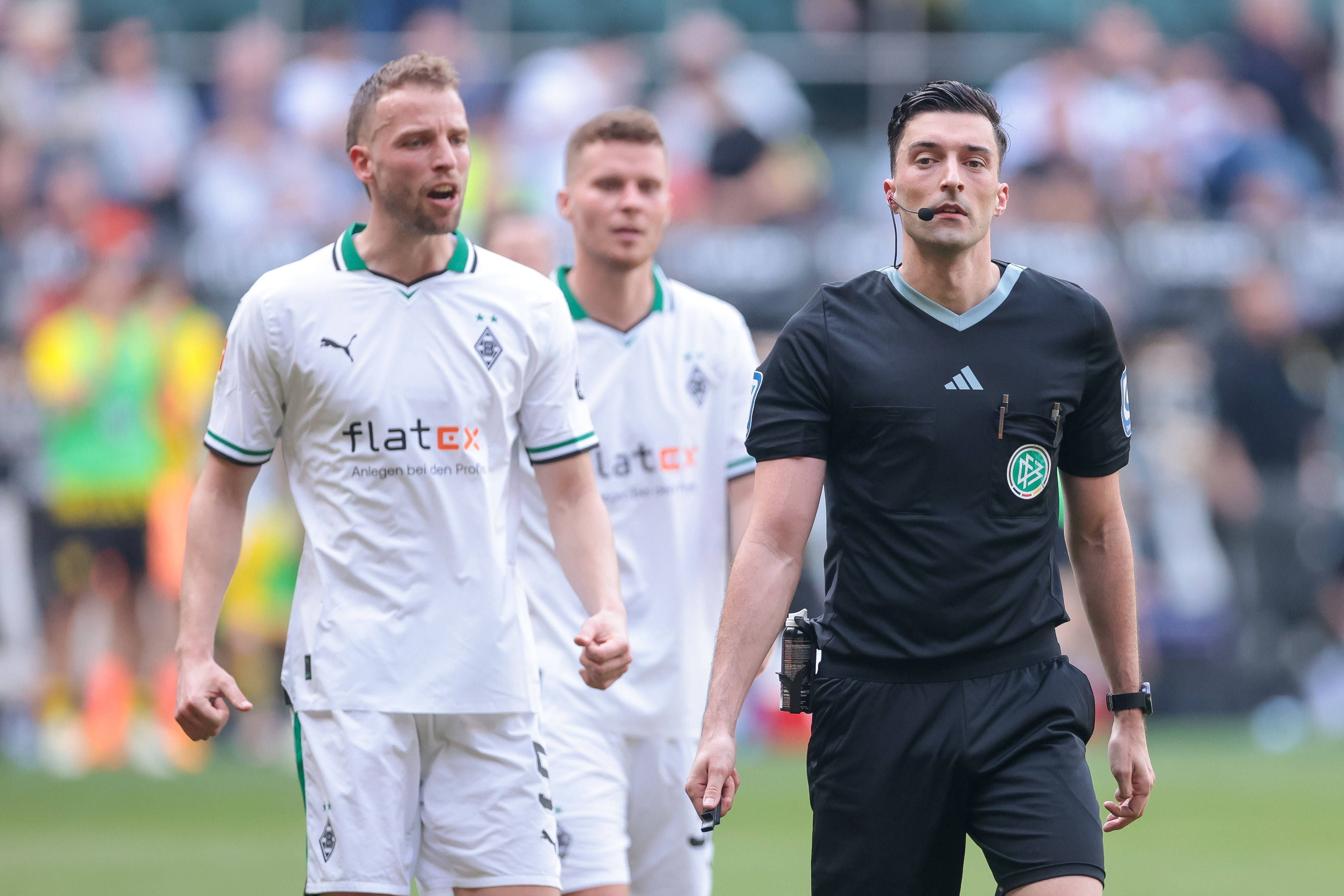 Schiedsrichter bei einem Spiel von Borussia Mönchengladbach. Im Hintergrund Marvin Friedrich und Nico Elvedi.