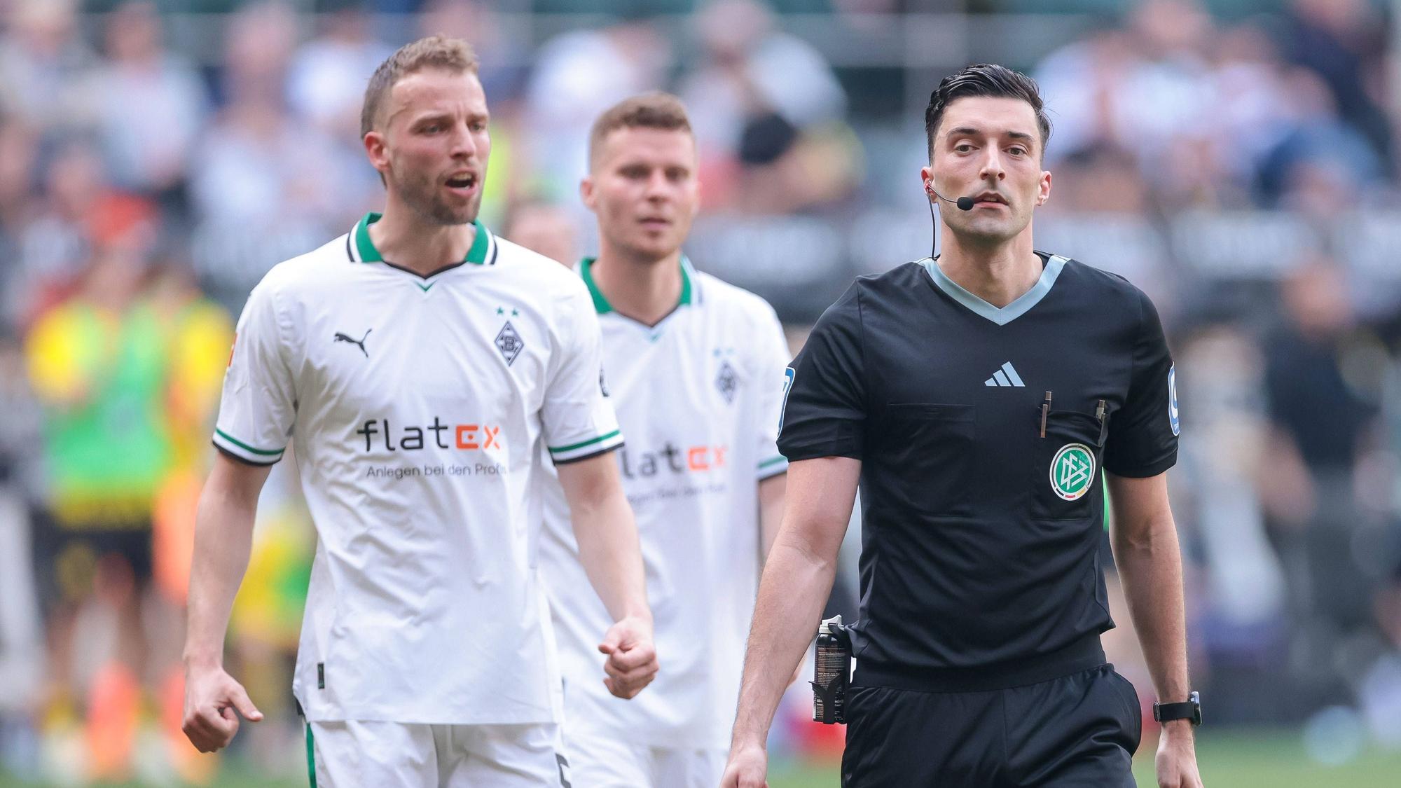 Schiedsrichter bei einem Spiel von Borussia Mönchengladbach. Im Hintergrund Marvin Friedrich und Nico Elvedi.