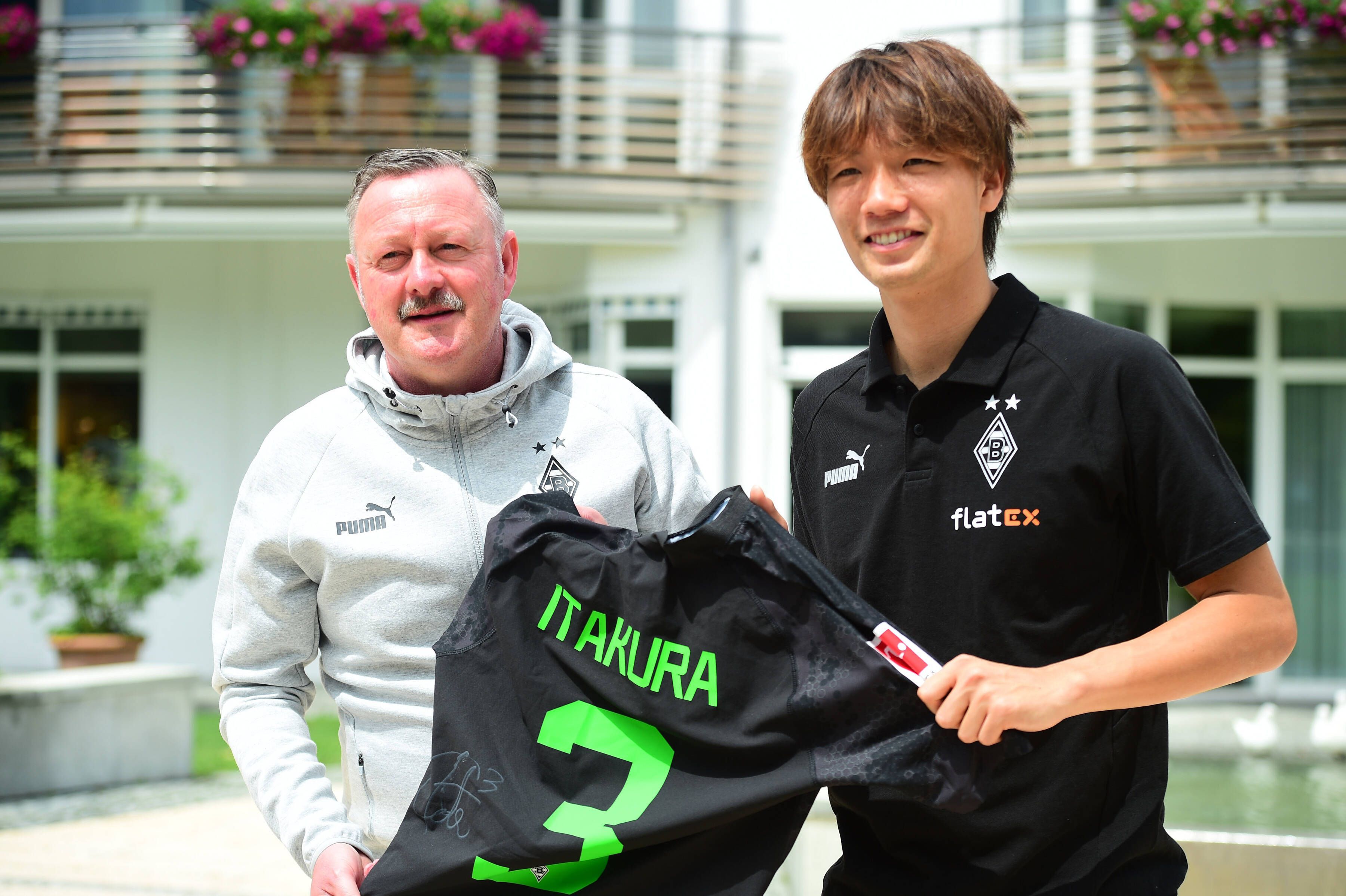 Roland Virkus und Ko Itakura halten ein Trikot des Japaners hoch.