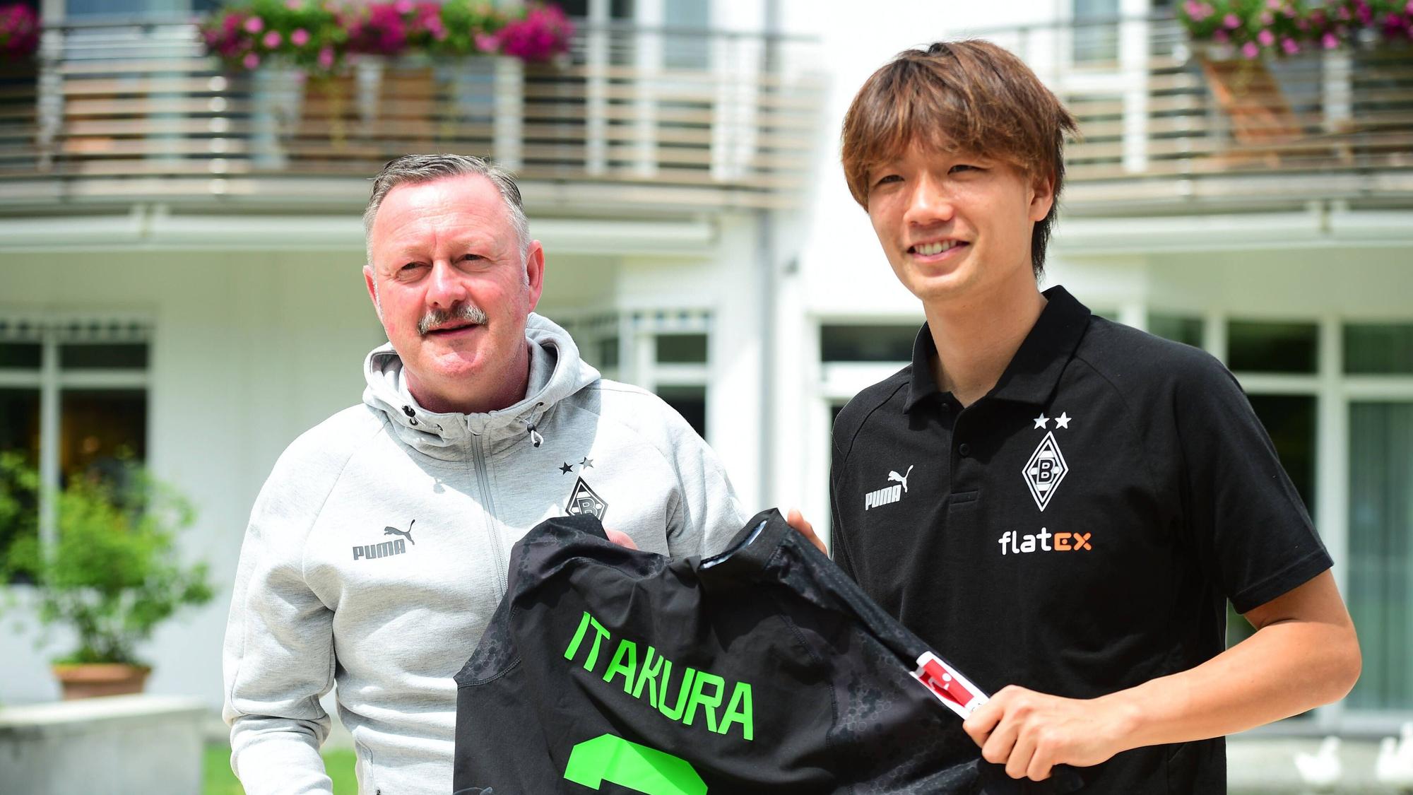 Roland Virkus und Ko Itakura halten ein Trikot des Japaners hoch.