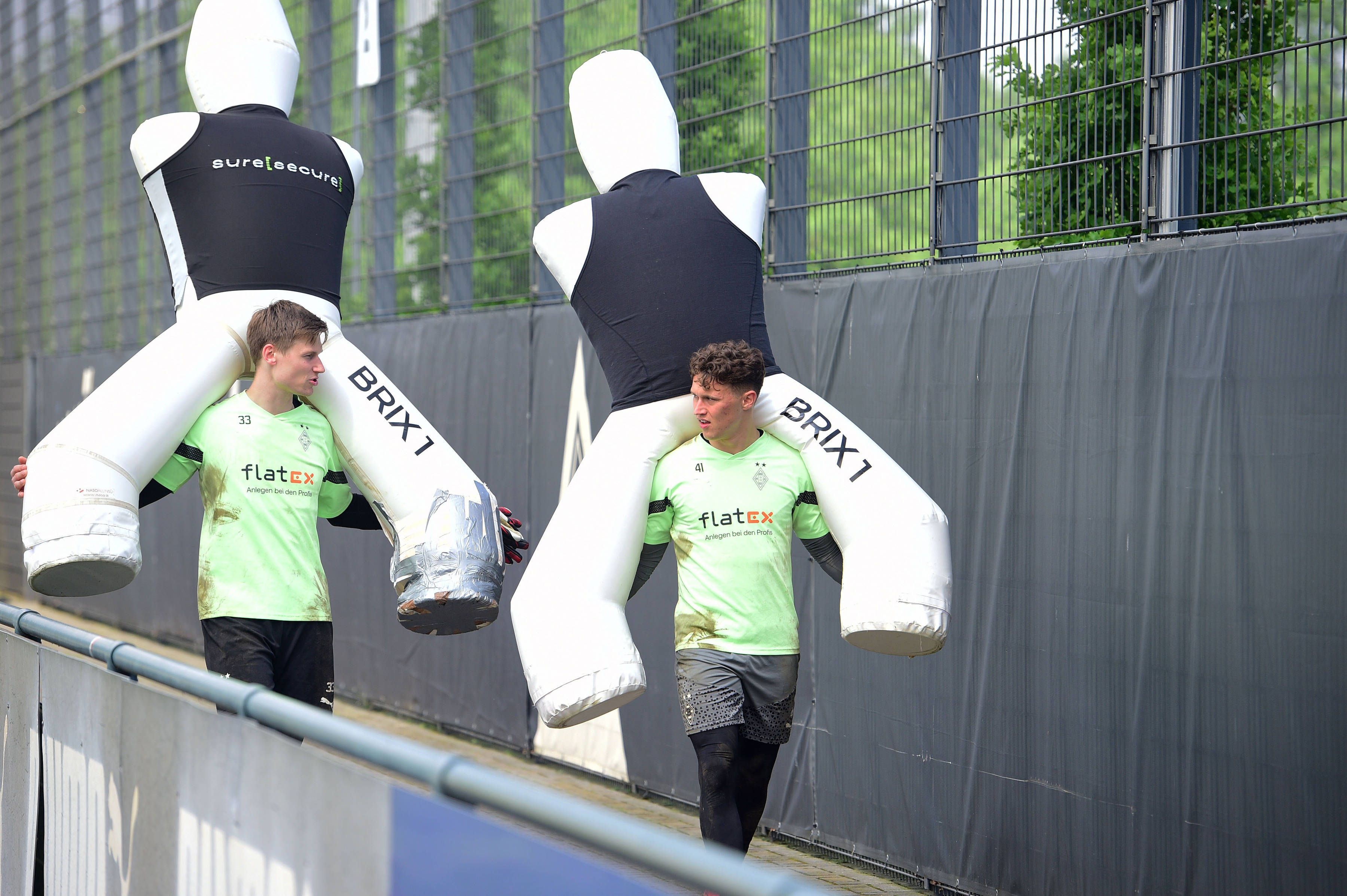 Moritz Nicolas und Jan Olschowsky tragen große Aufsteller für das Training auf ihren Schultern.