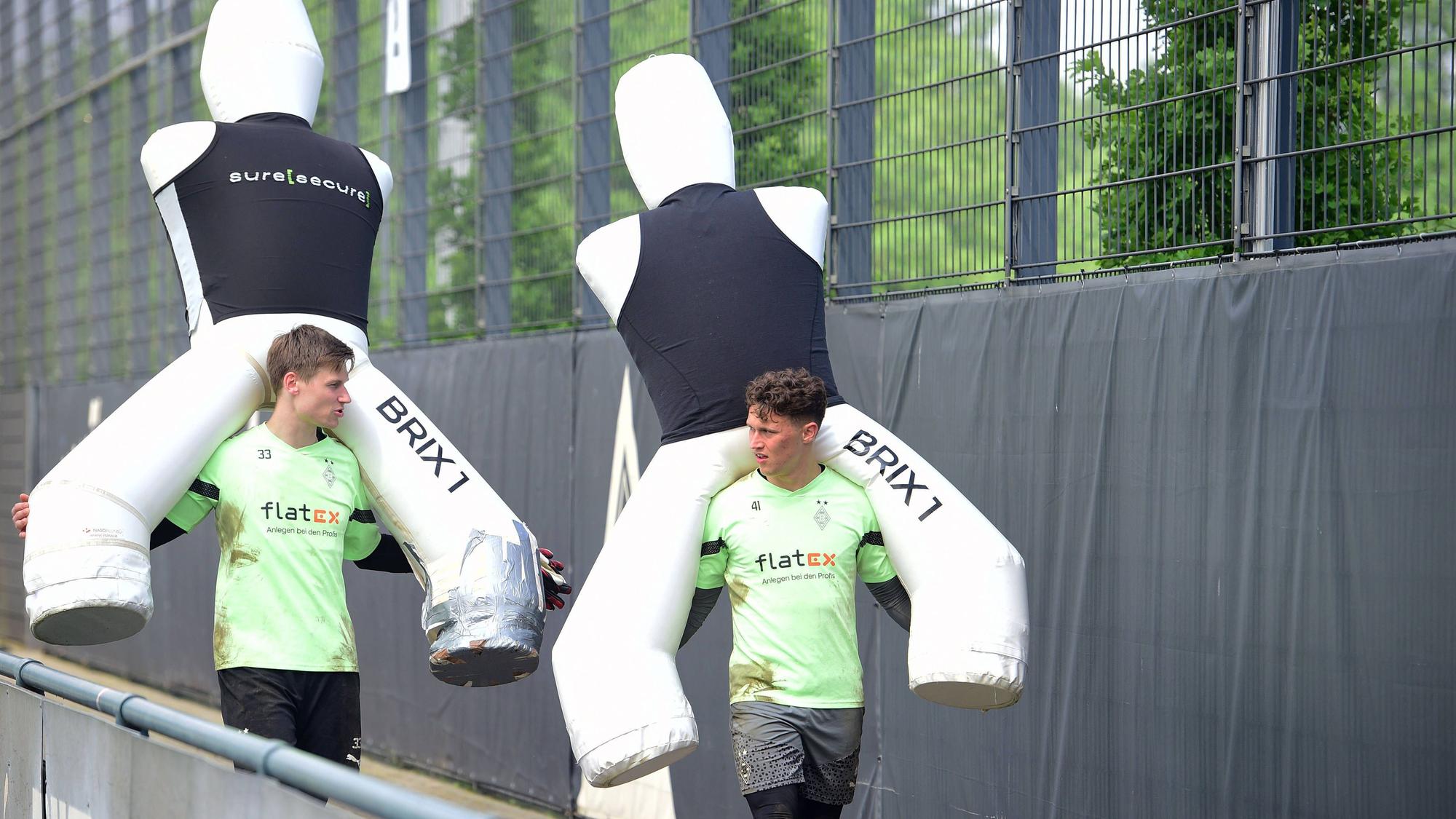 Moritz Nicolas und Jan Olschowsky tragen große Aufsteller für das Training auf ihren Schultern.