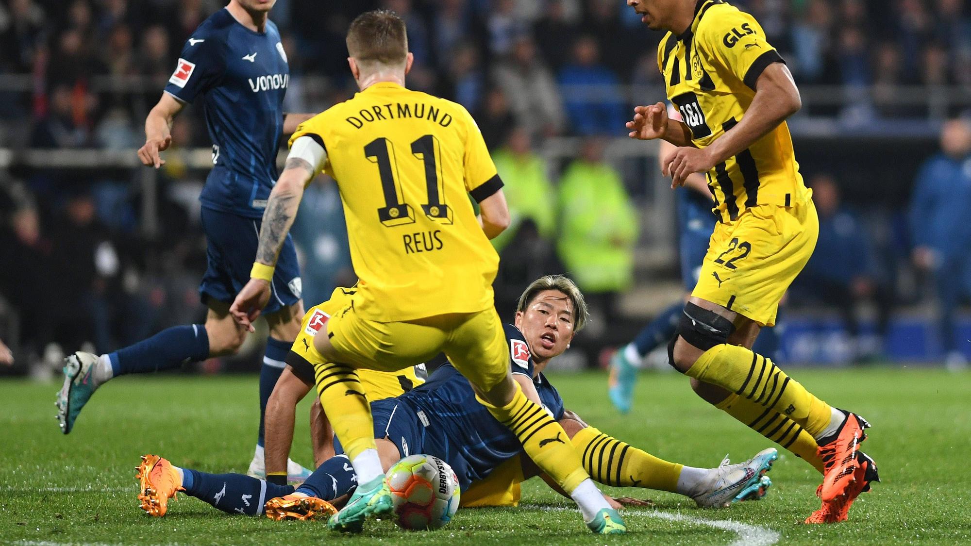 Takuma Asano grätscht einen Ball gegen Marco Reus.