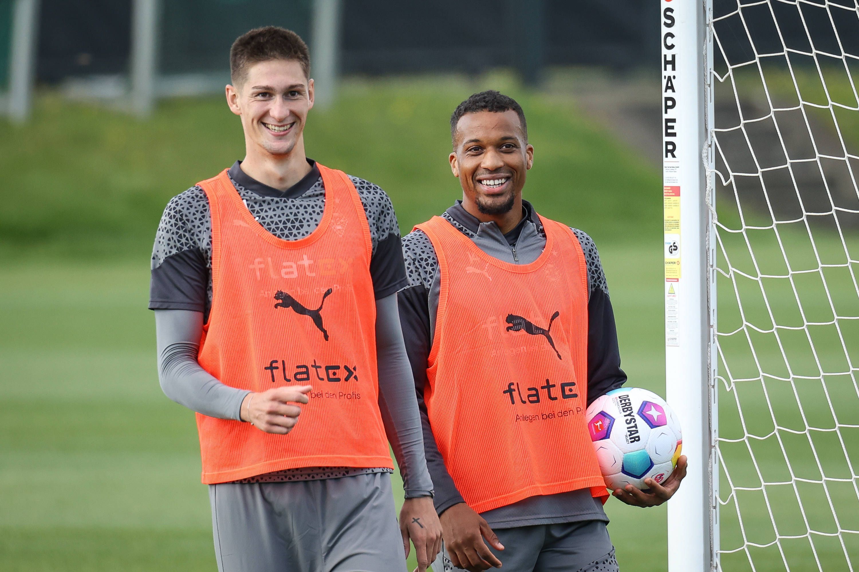 Die Gladbach-Profis Alassane Plea und Tomas Cvancara stehen lachend nebeneinander auf dem Trainingsplatz.