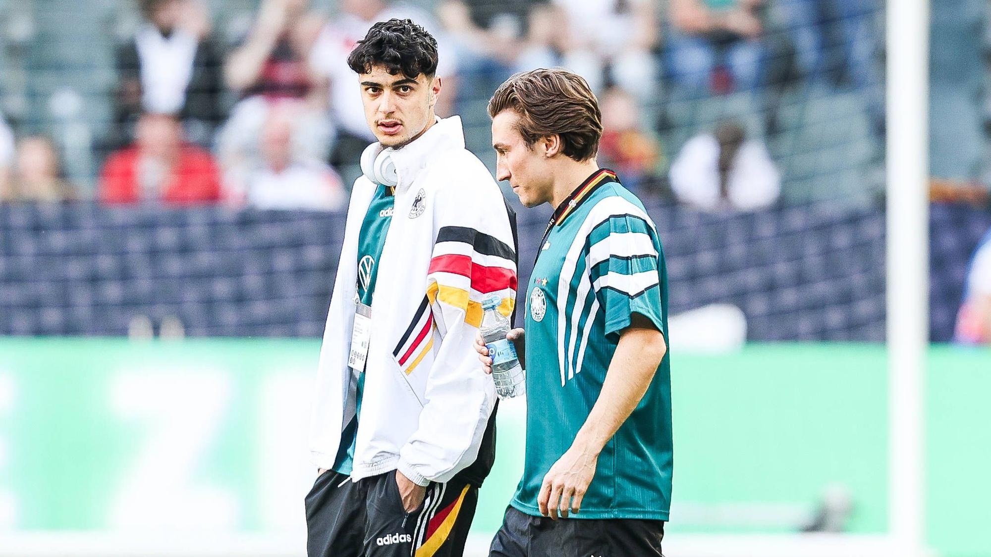 Aleksandar Pavlovic (l.) und Rocco Reitz gehen nebeneinander über den Platz.