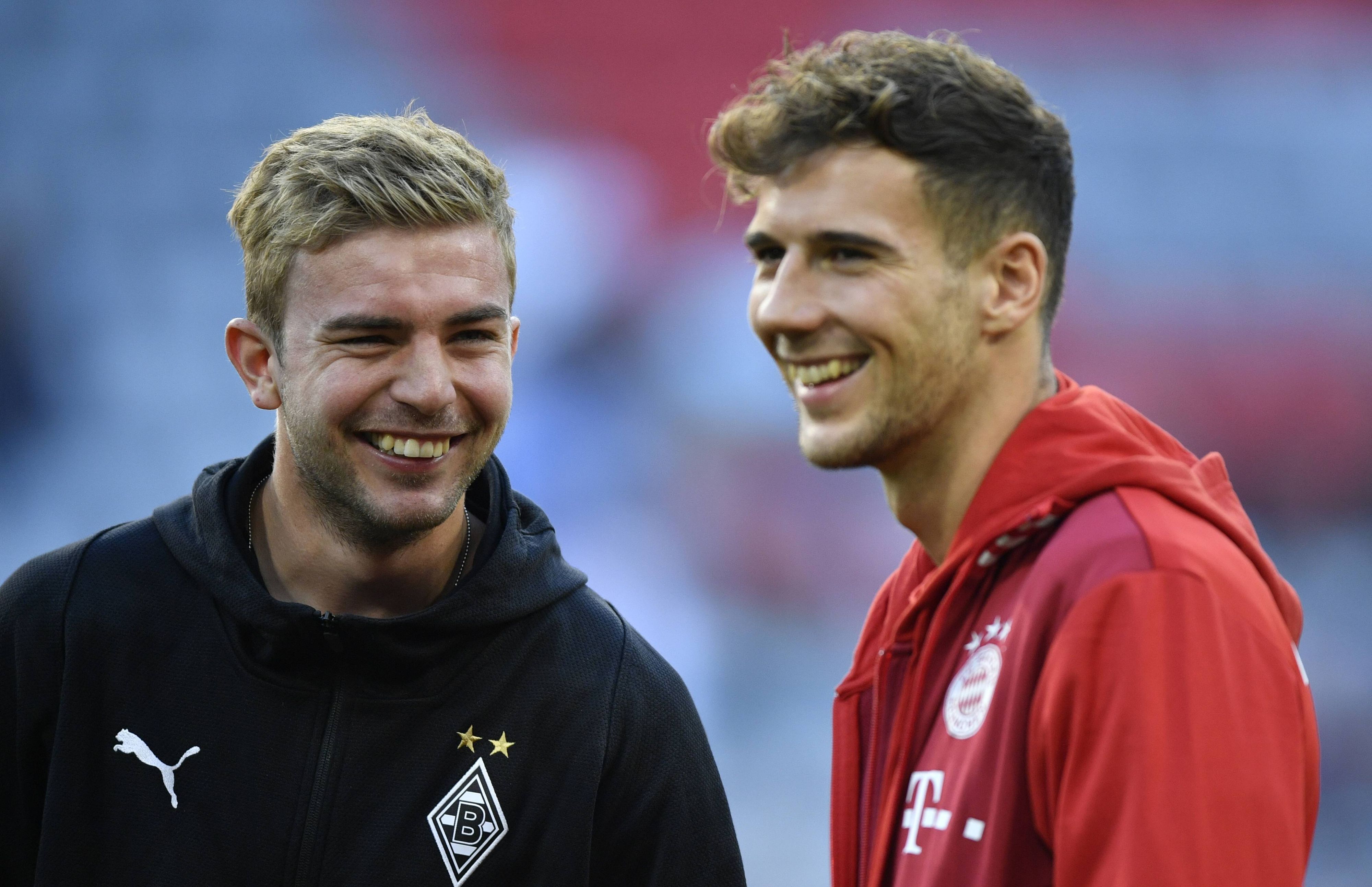 Borussia Mönchengladbachs Christoph Kramer und Bayerns Leon Goretzka stehen gemeinsam lachend auf dem Platz.