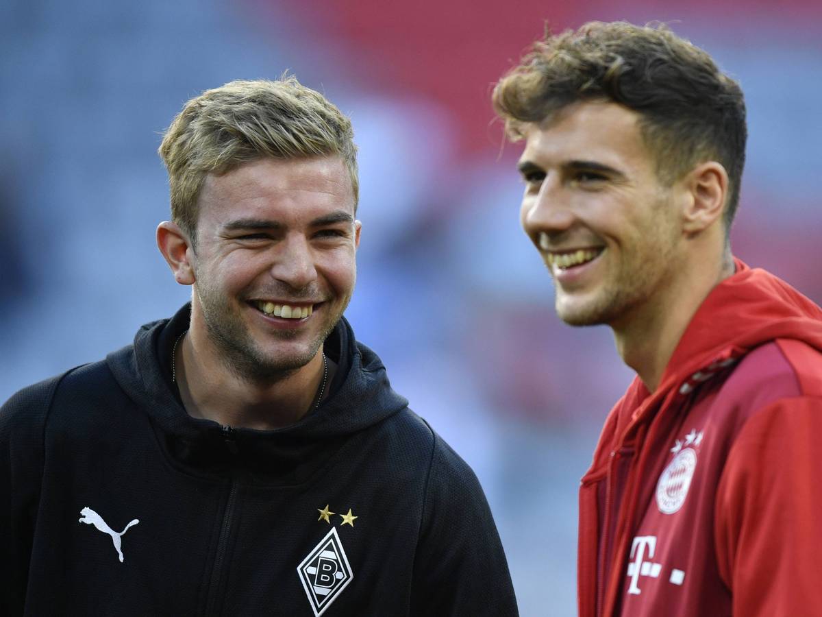 Borussia Mönchengladbachs Christoph Kramer und Bayerns Leon Goretzka stehen gemeinsam lachend auf dem Platz.