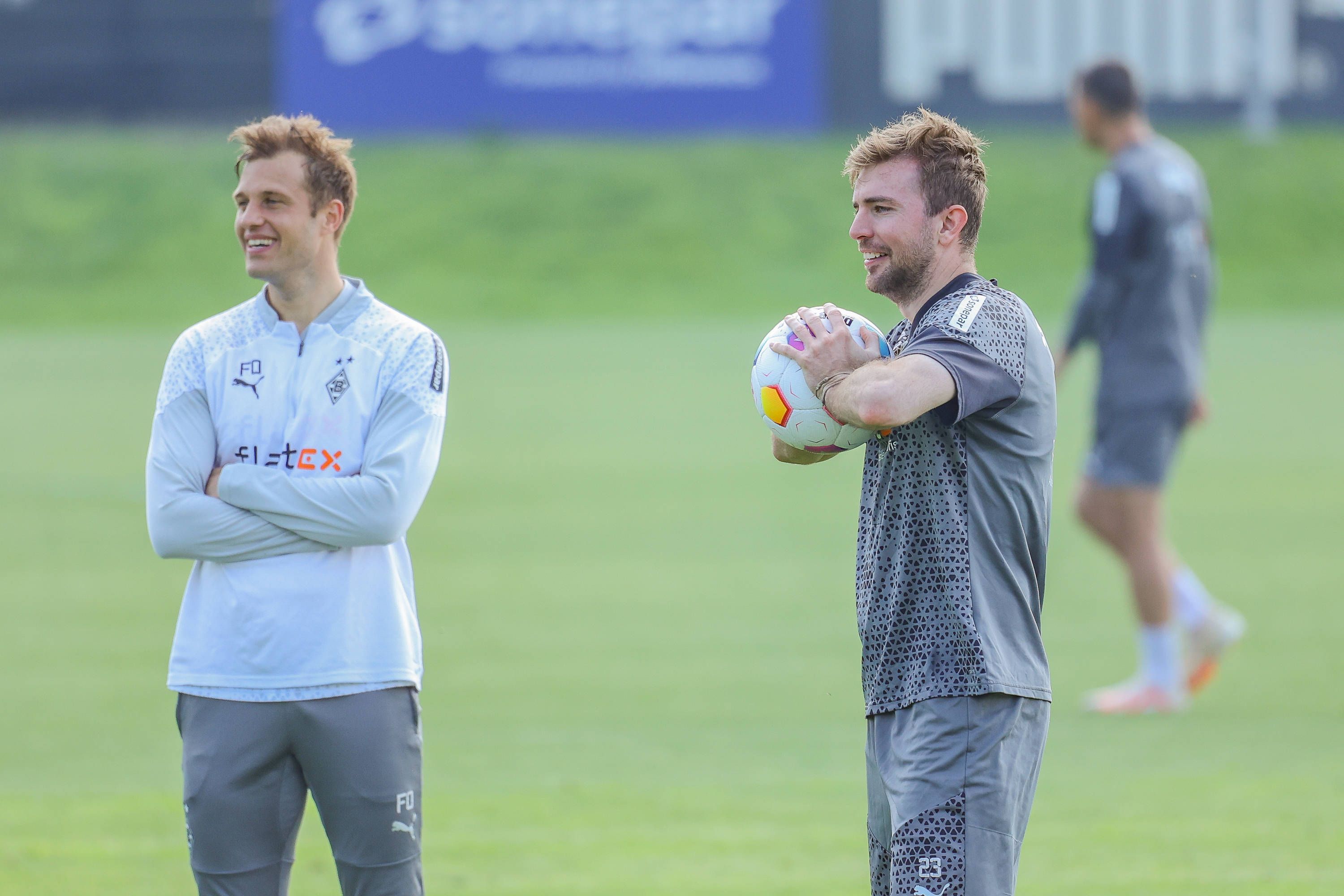 Gladbachs Mittelfeldspieler Christoph Kramer und Torwarttrainer Fabian Otte stehen gemeinsam lachend auf dem Trainingsplatz.