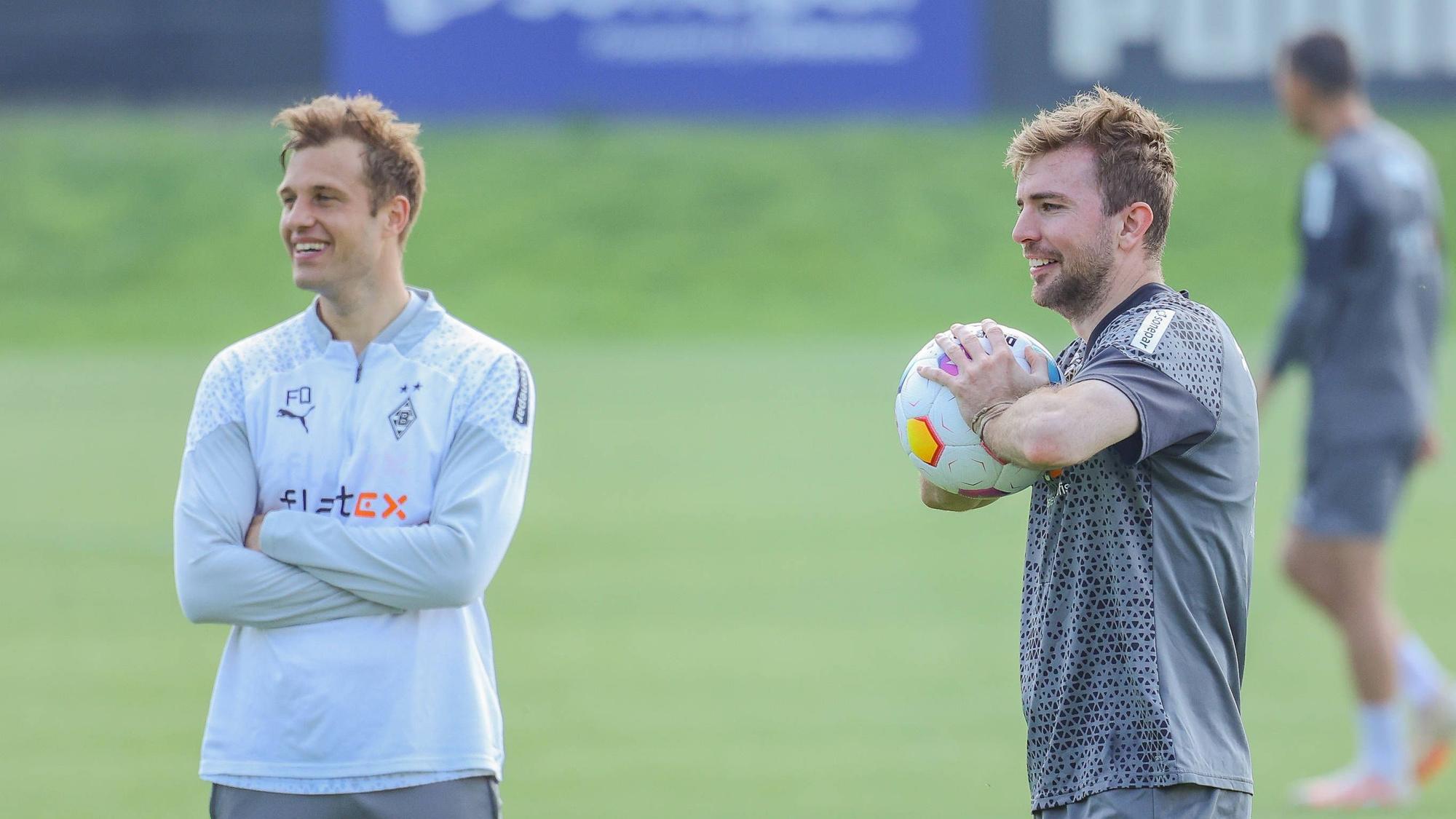 Gladbachs Mittelfeldspieler Christoph Kramer und Torwarttrainer Fabian Otte stehen gemeinsam lachend auf dem Trainingsplatz.